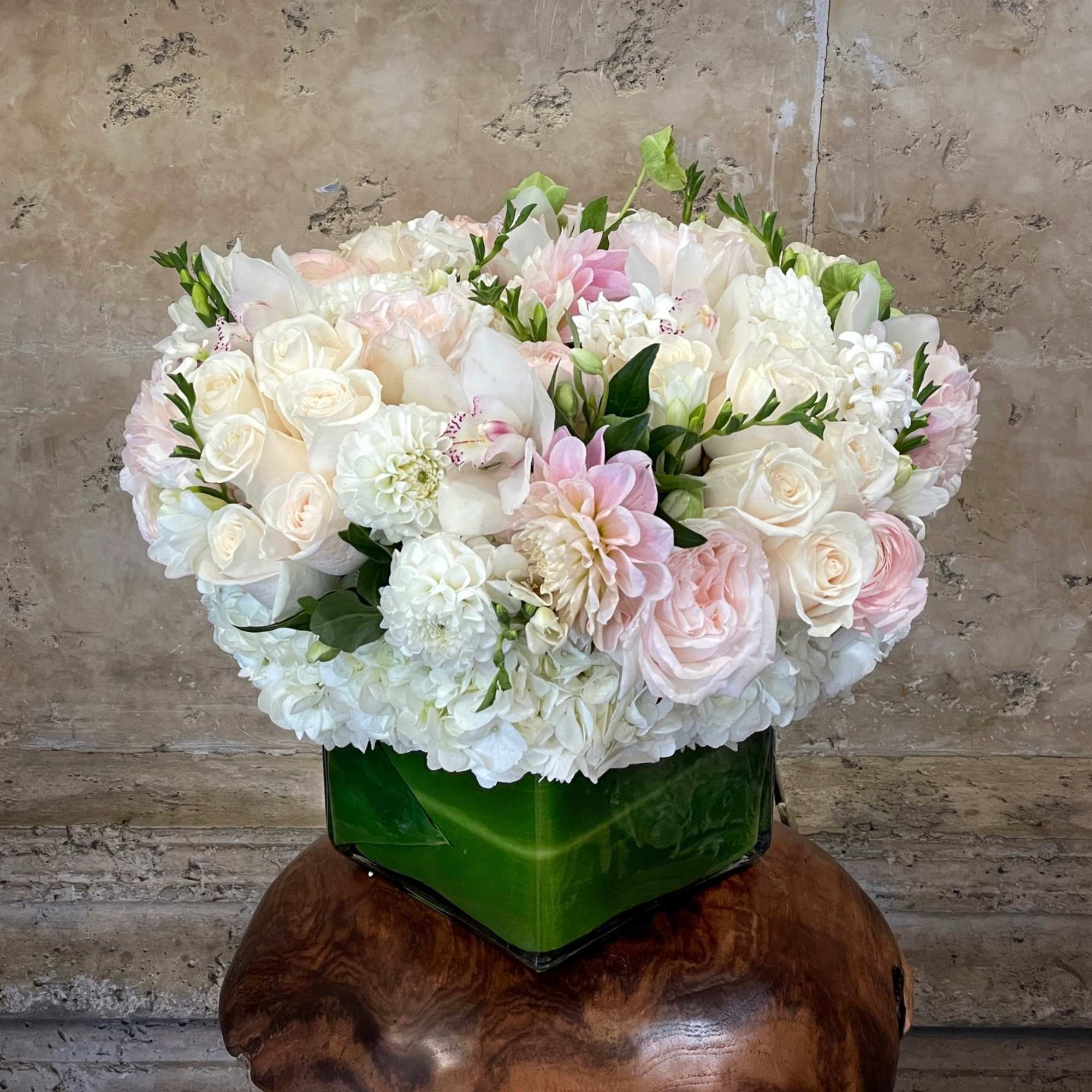 Round bouquet of white and blush flowers in a green vase