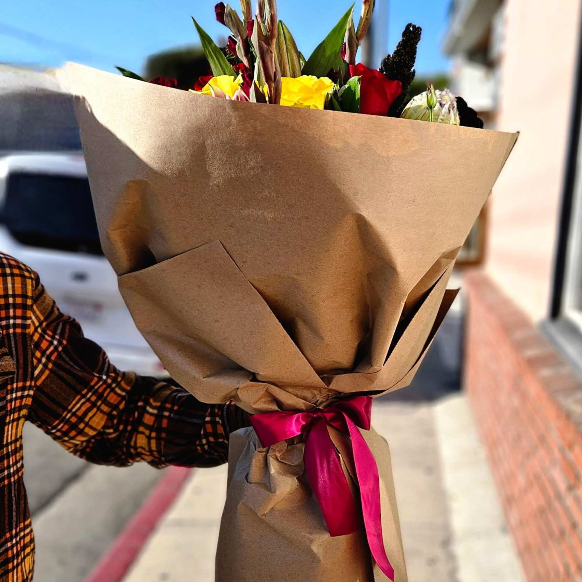Wrapped bouquet of mixed flowers with a pink ribbon