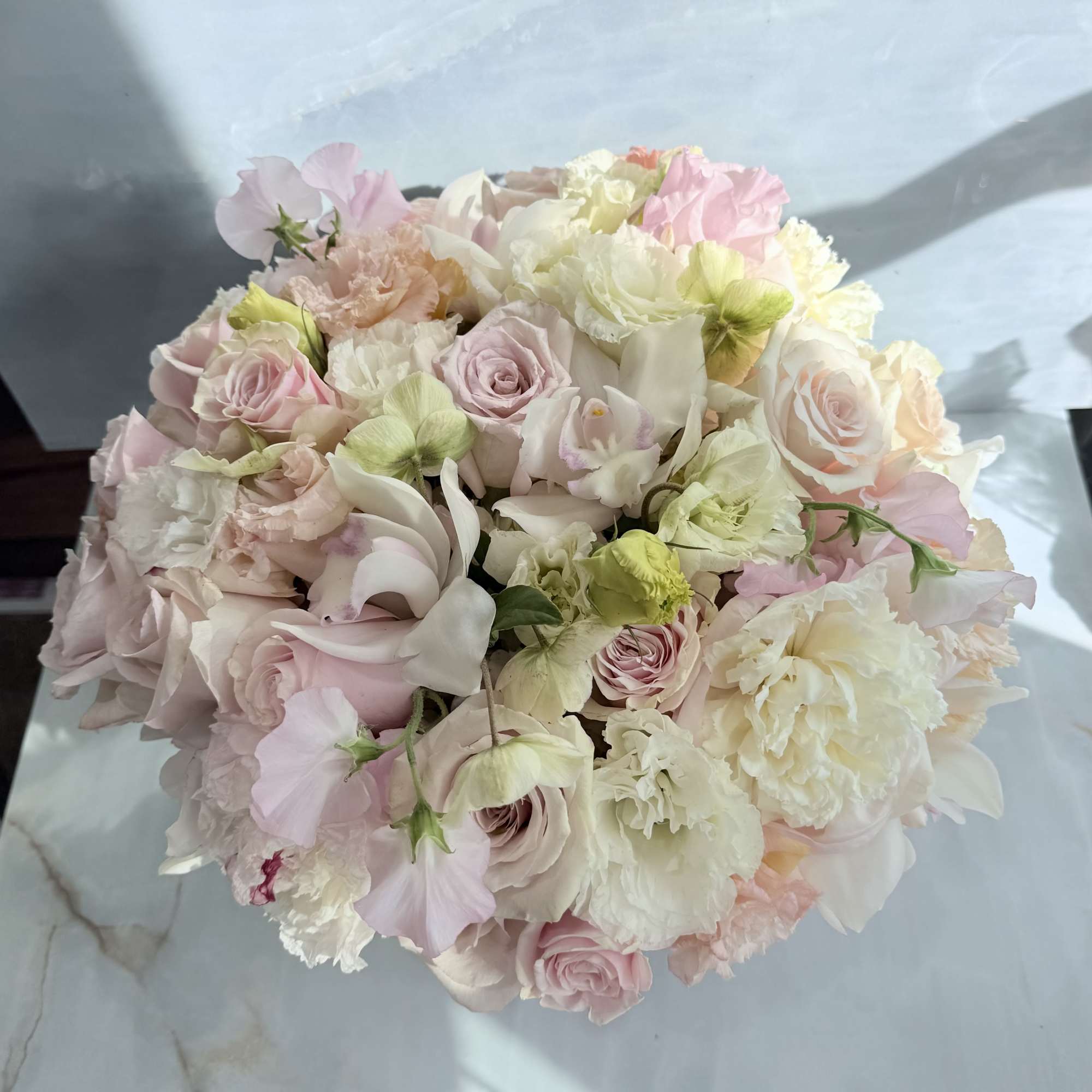Round bouquet of pale pink and white flowers with soft pastel accents