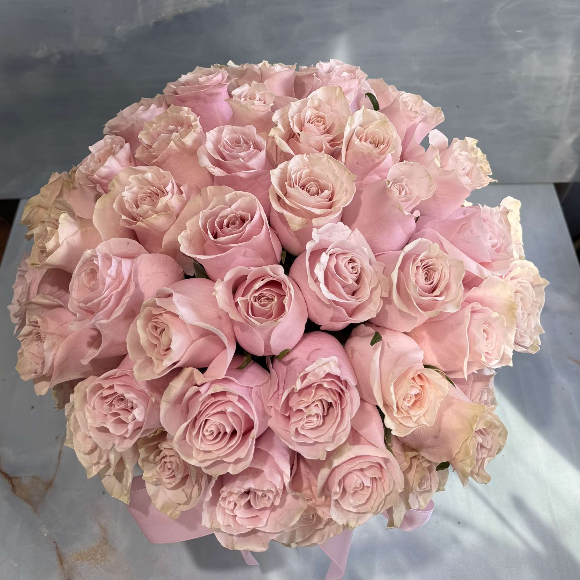 Round bouquet of pale pink roses tied with a pink ribbon