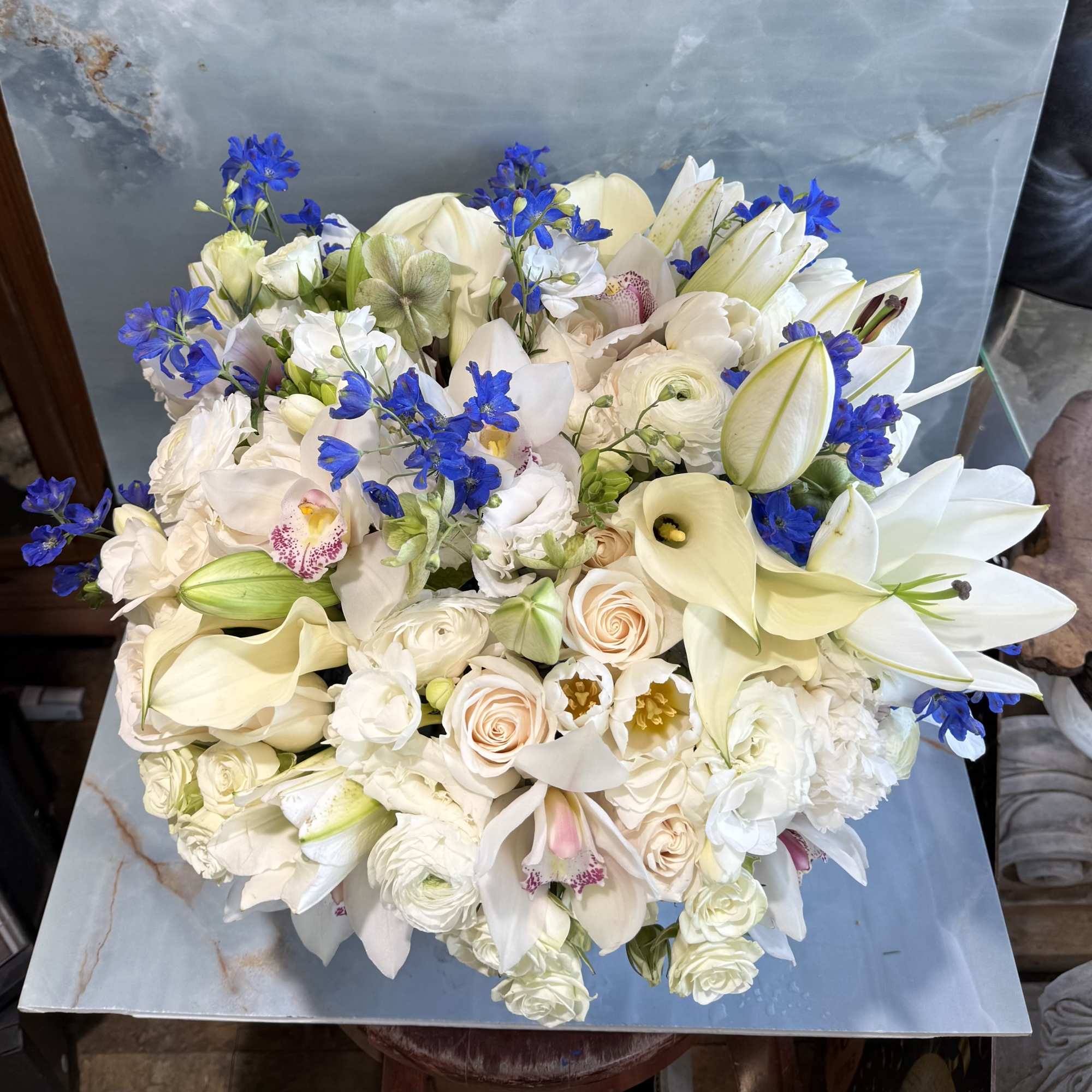 Large bouquet of white and cream flowers with bright blue accents