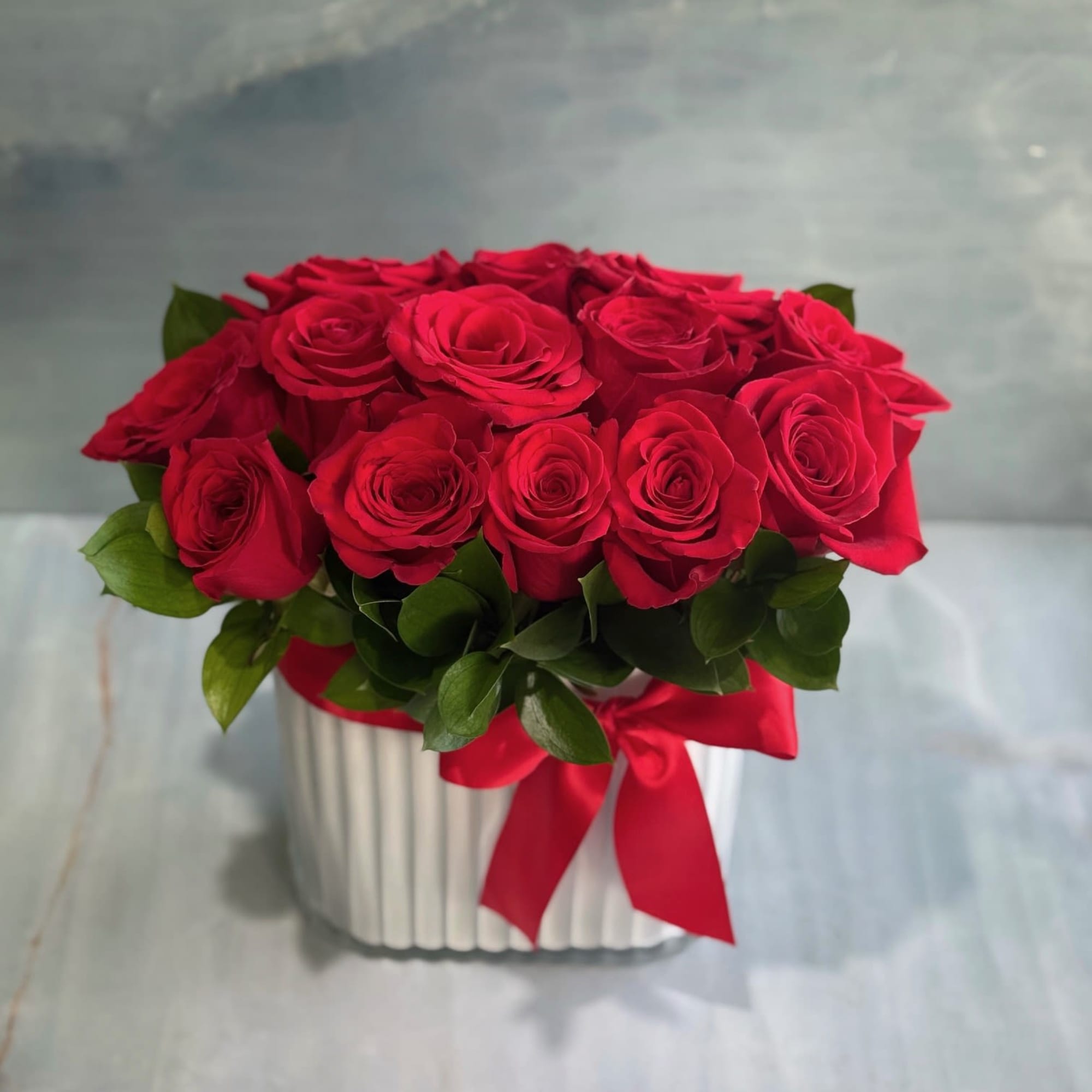 Red roses arranged in a white box with a red ribbon