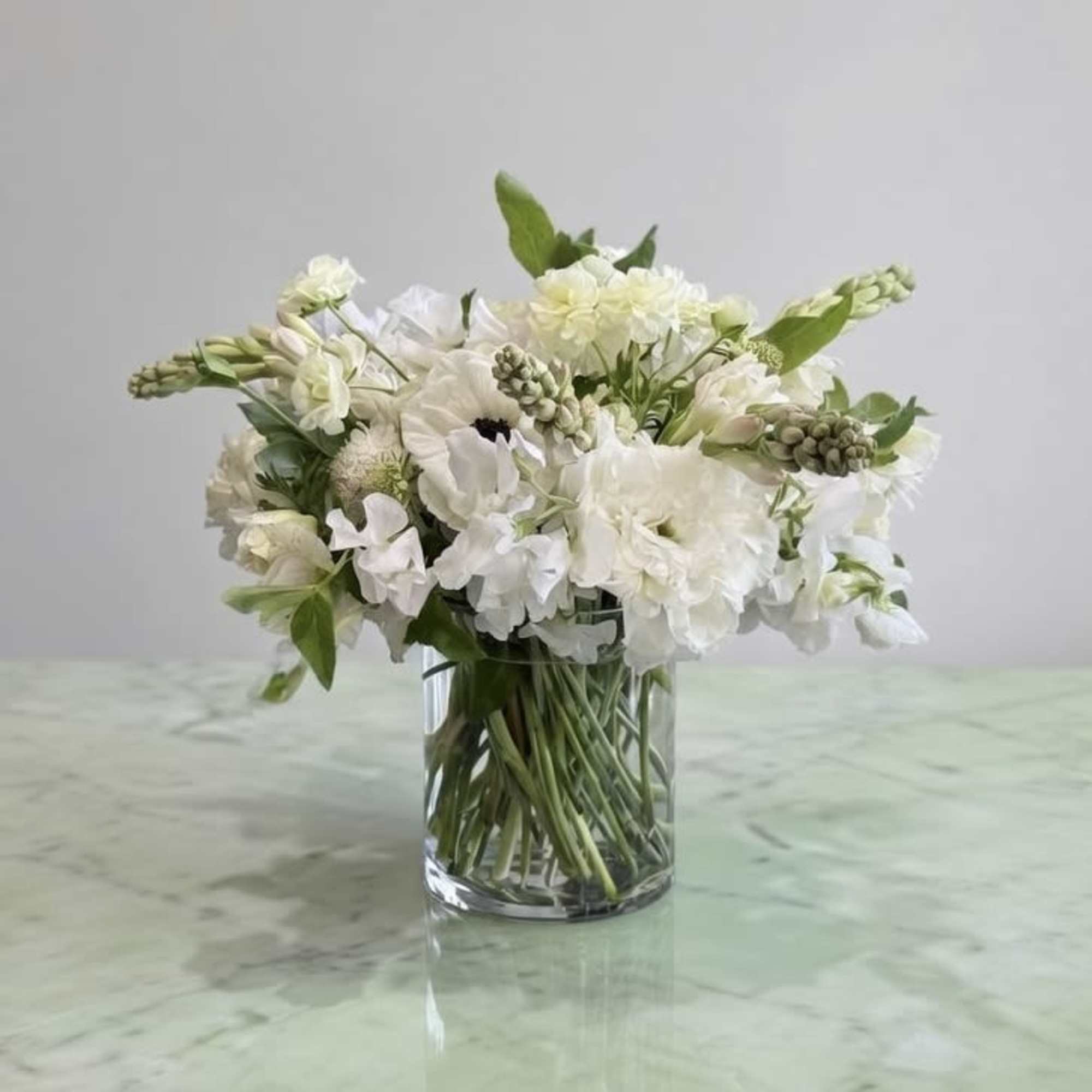Lisianthus, Dahlias, Sweet Pea, and more white flower with greenery in glass