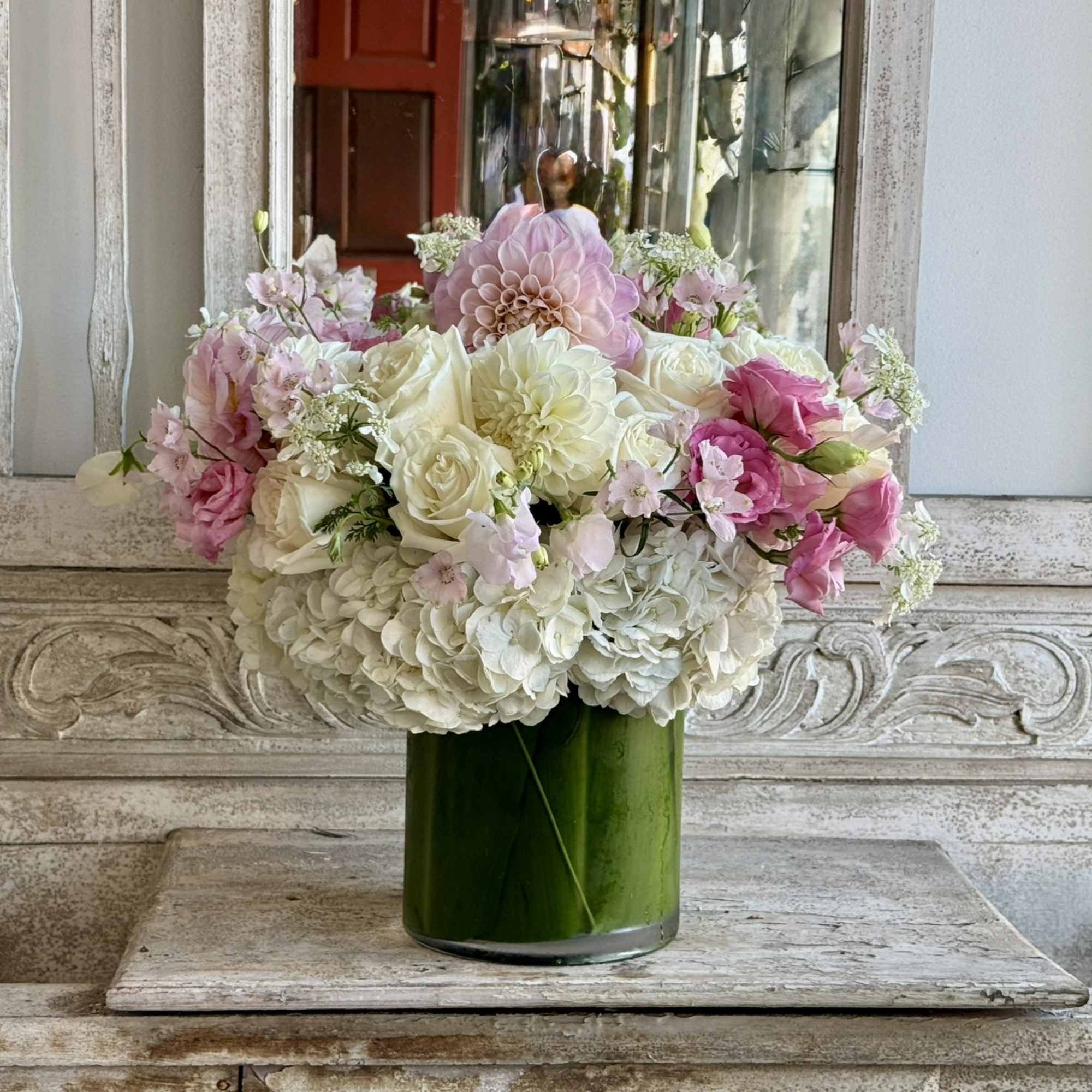 Pink and white flower arrangement in a green glass vase