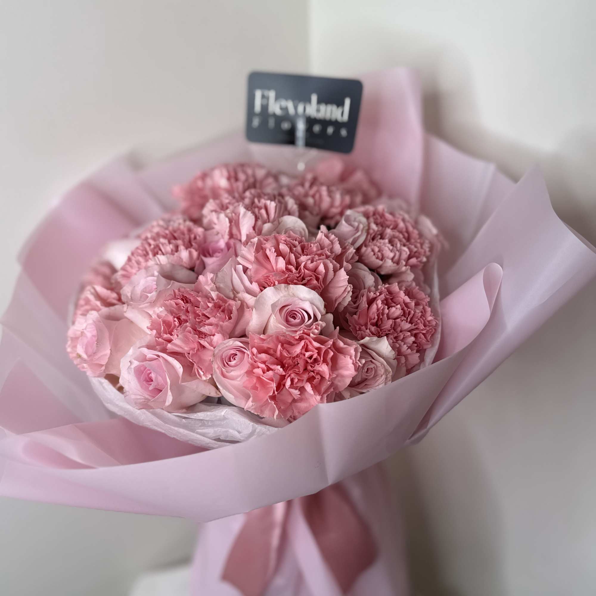 Pink bouquet of roses and carnations wrapped in pale pink paper