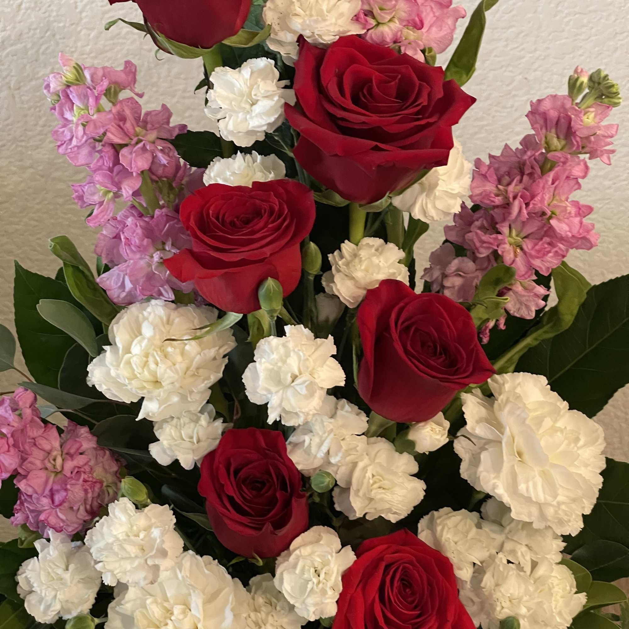 Deep, velvety red roses rise through clusters of soft white carnations and, photo 2 of 2