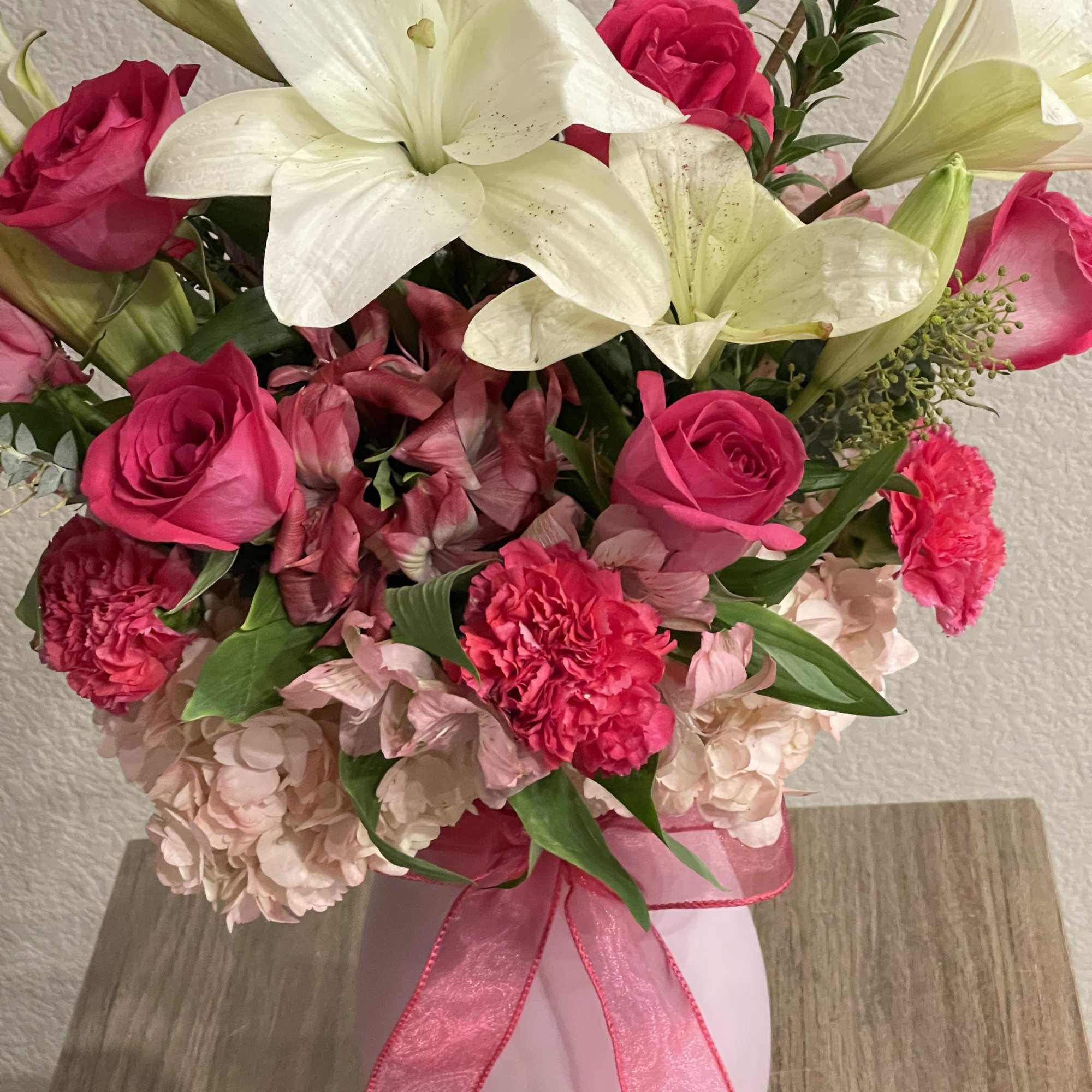 Bright white lilies rise above vivid hot-pink roses and carnations in this, photo 2 of 2