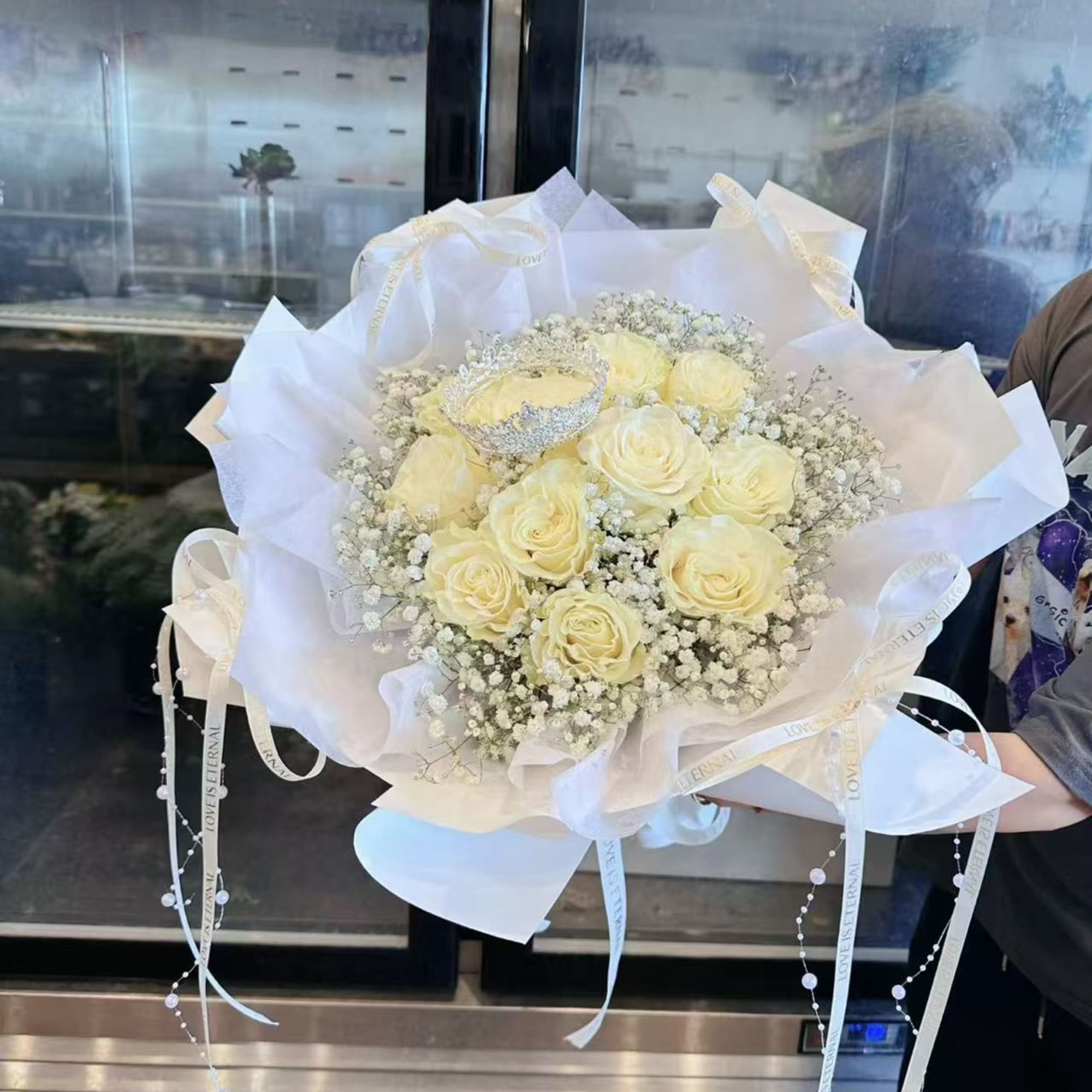 Bouquet of pale yellow roses wrapped in white paper with ribbon accents