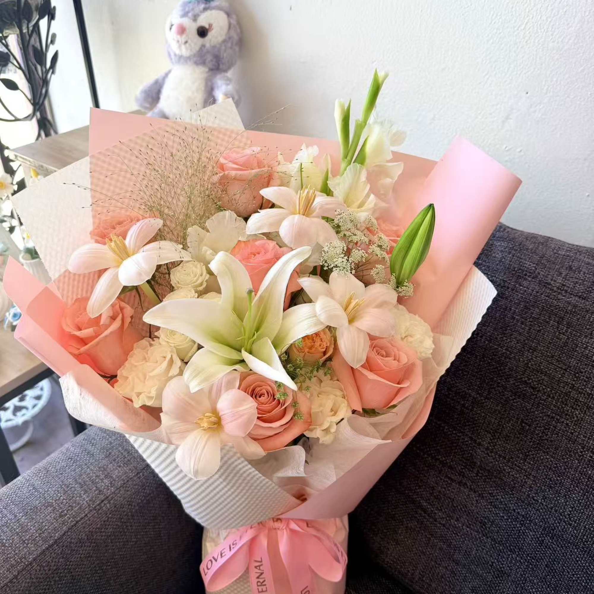 Pink and white bouquet with roses and lilies wrapped in pastel paper
