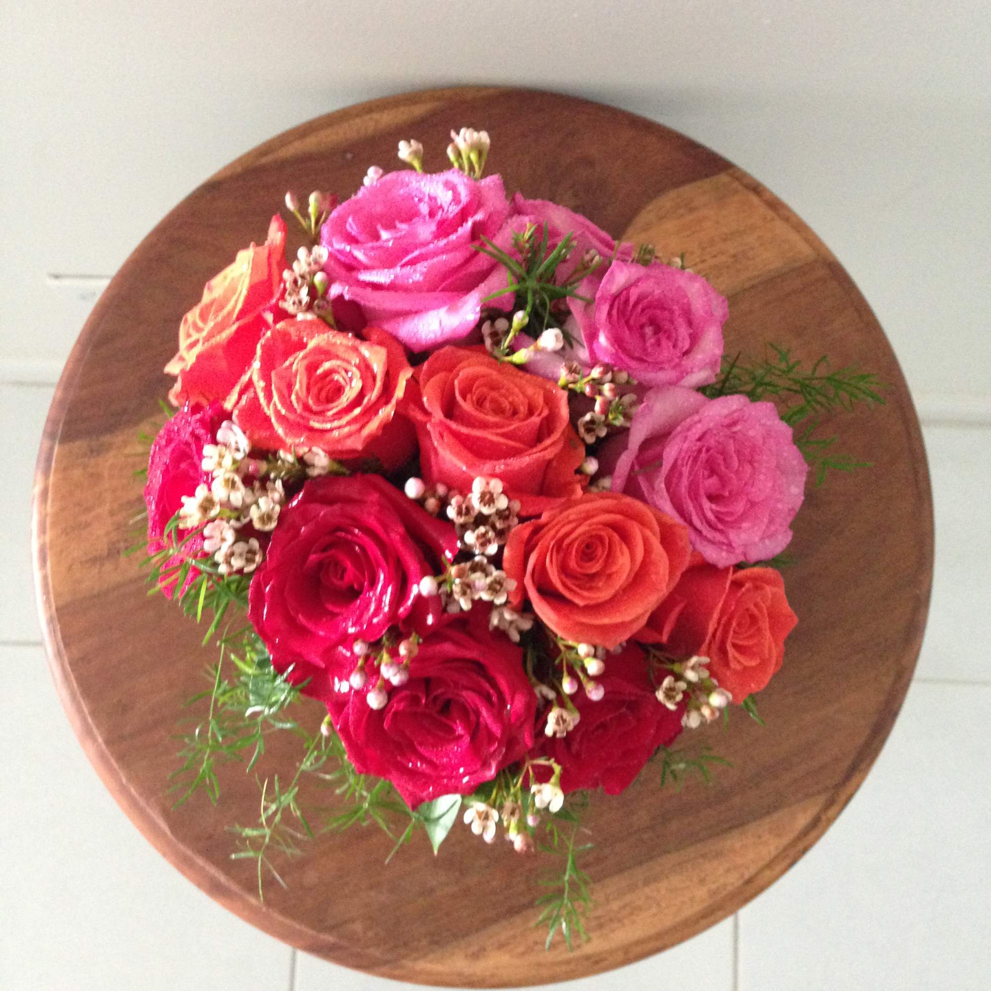 Round bouquet of pink and coral roses on a wooden surface