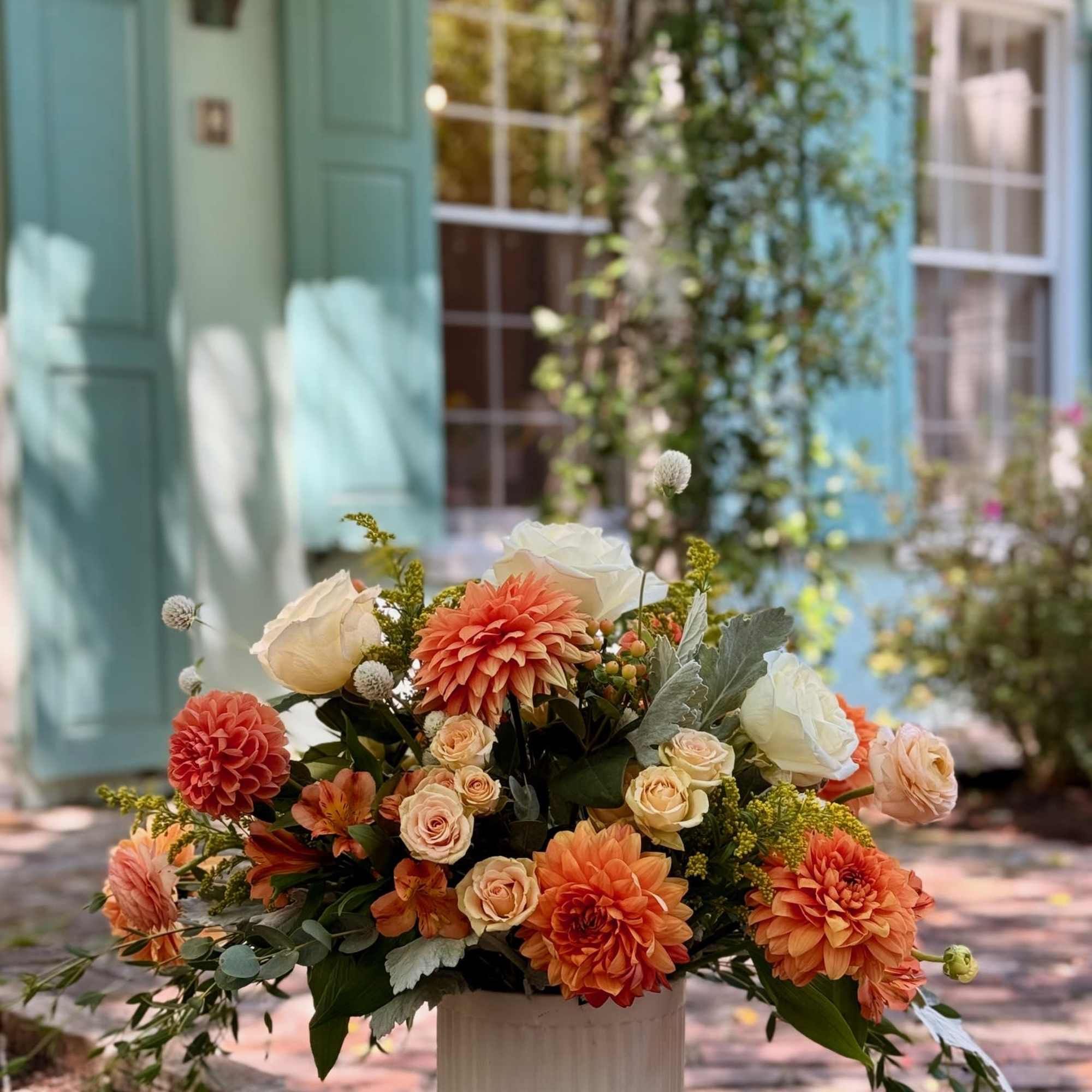 Orange and white floral arrangement in a white pedestal vase