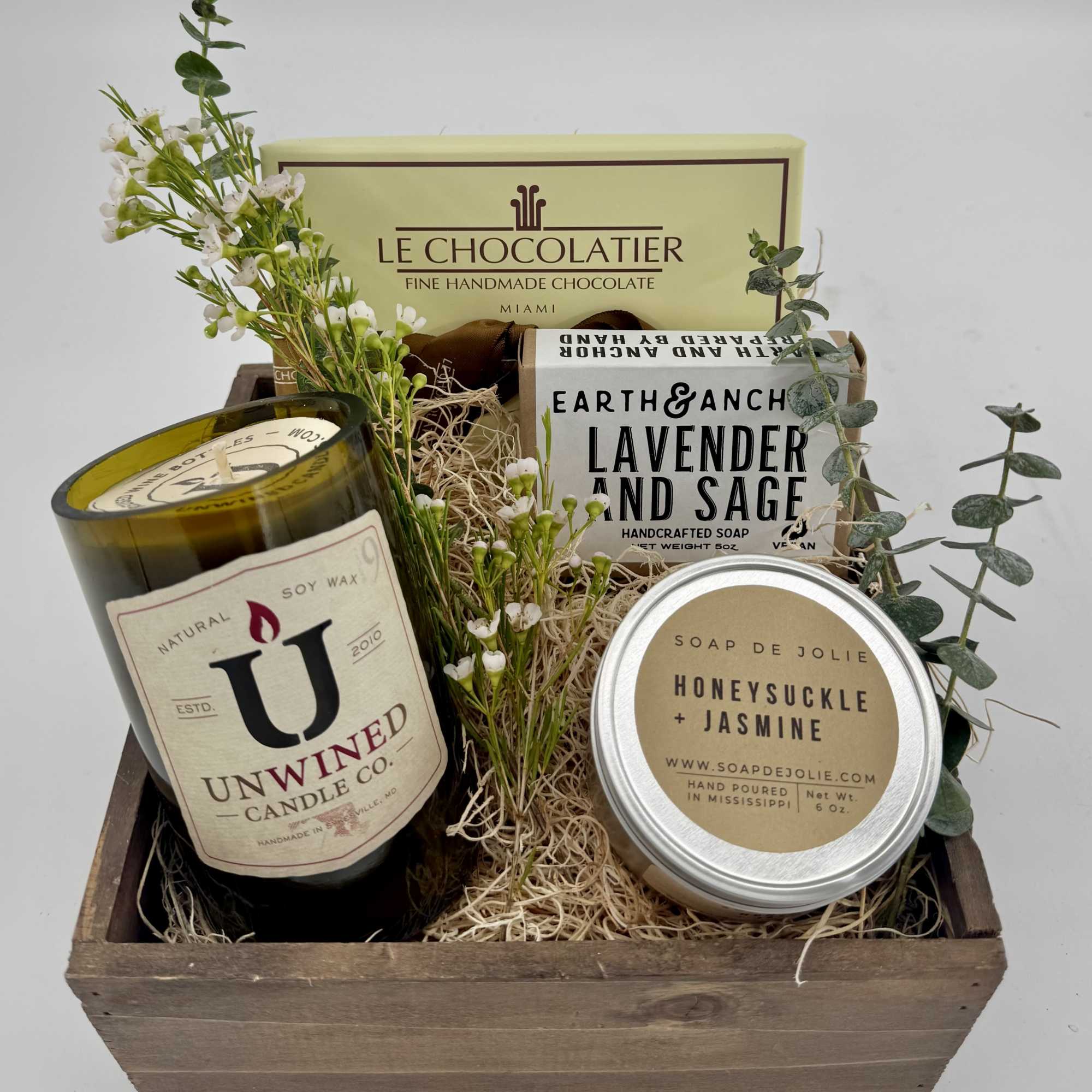 Gift basket with candles, soaps, chocolates, and small white flowers