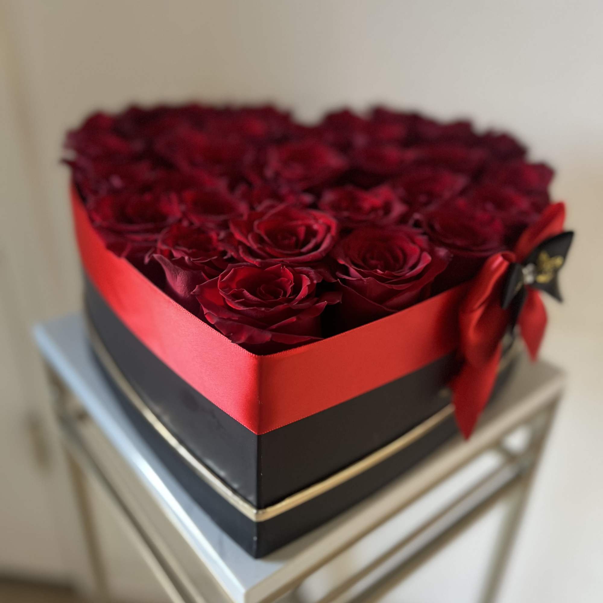 Heart-shaped box filled with red roses and tied with a red ribbon