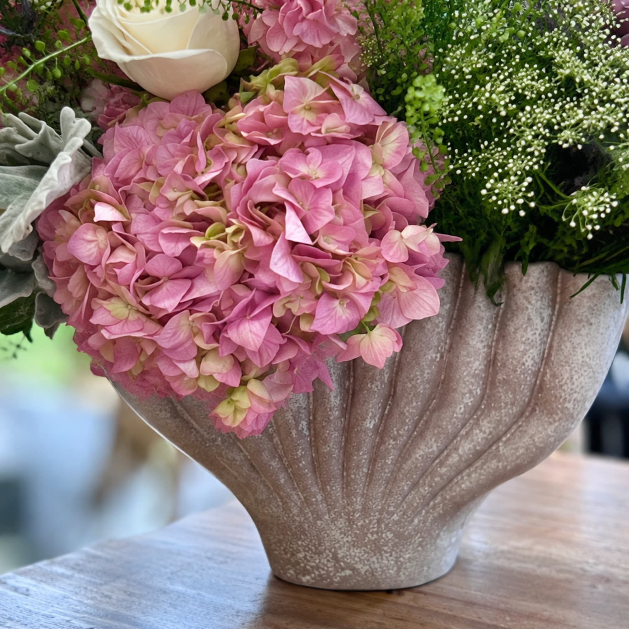 Pink hydrangeas and a white rose in a textured vase