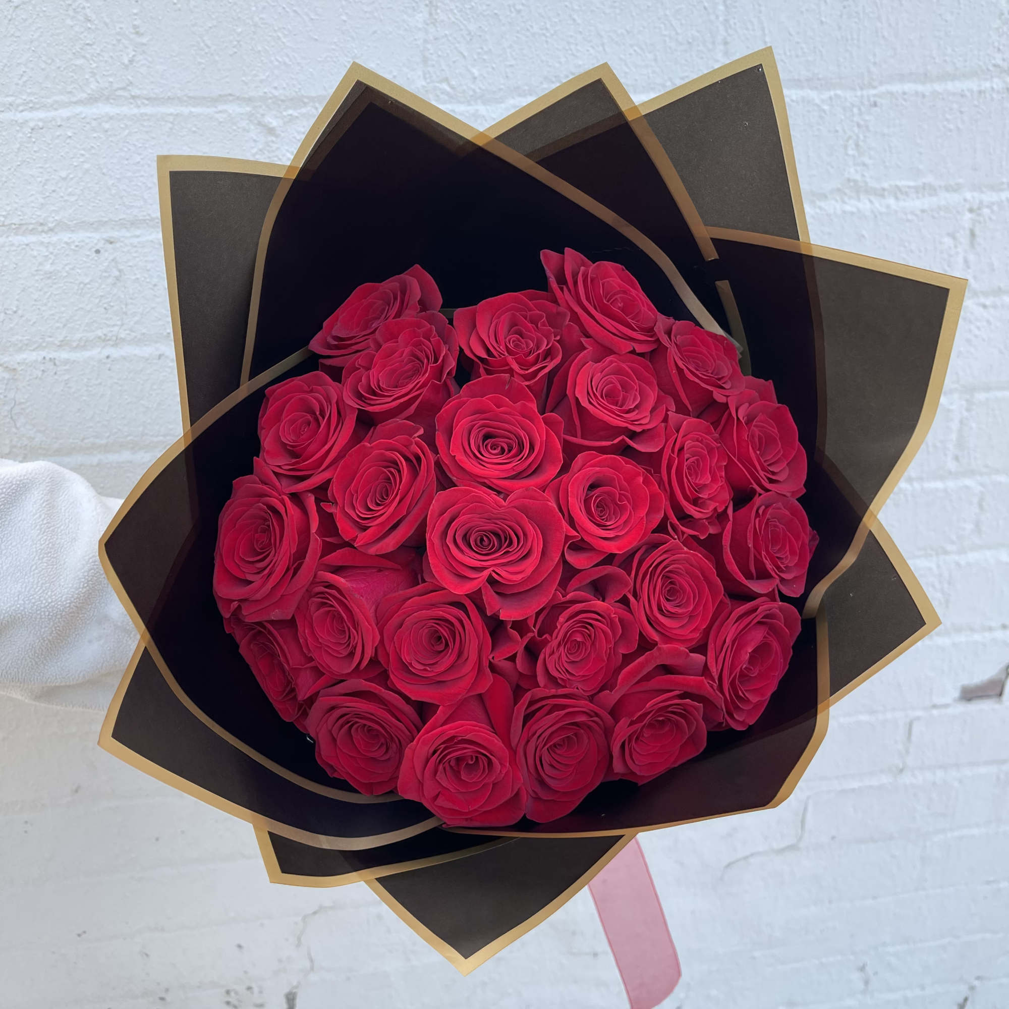Bouquet of red roses wrapped in black paper with gold trim
