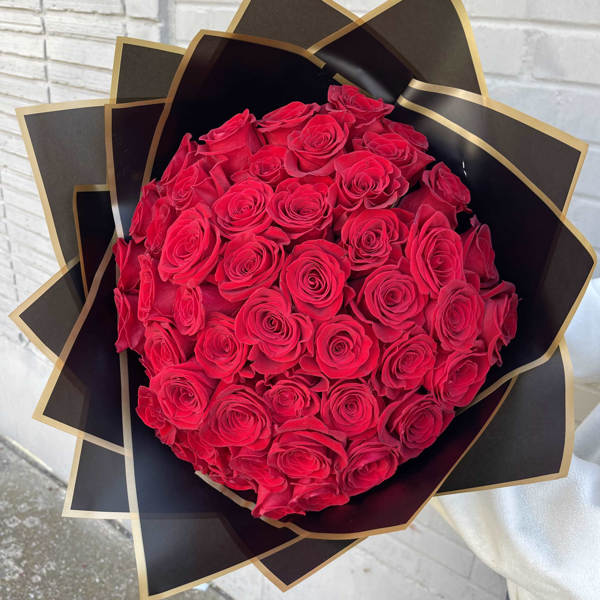 Large bouquet of red roses wrapped in black and gold paper