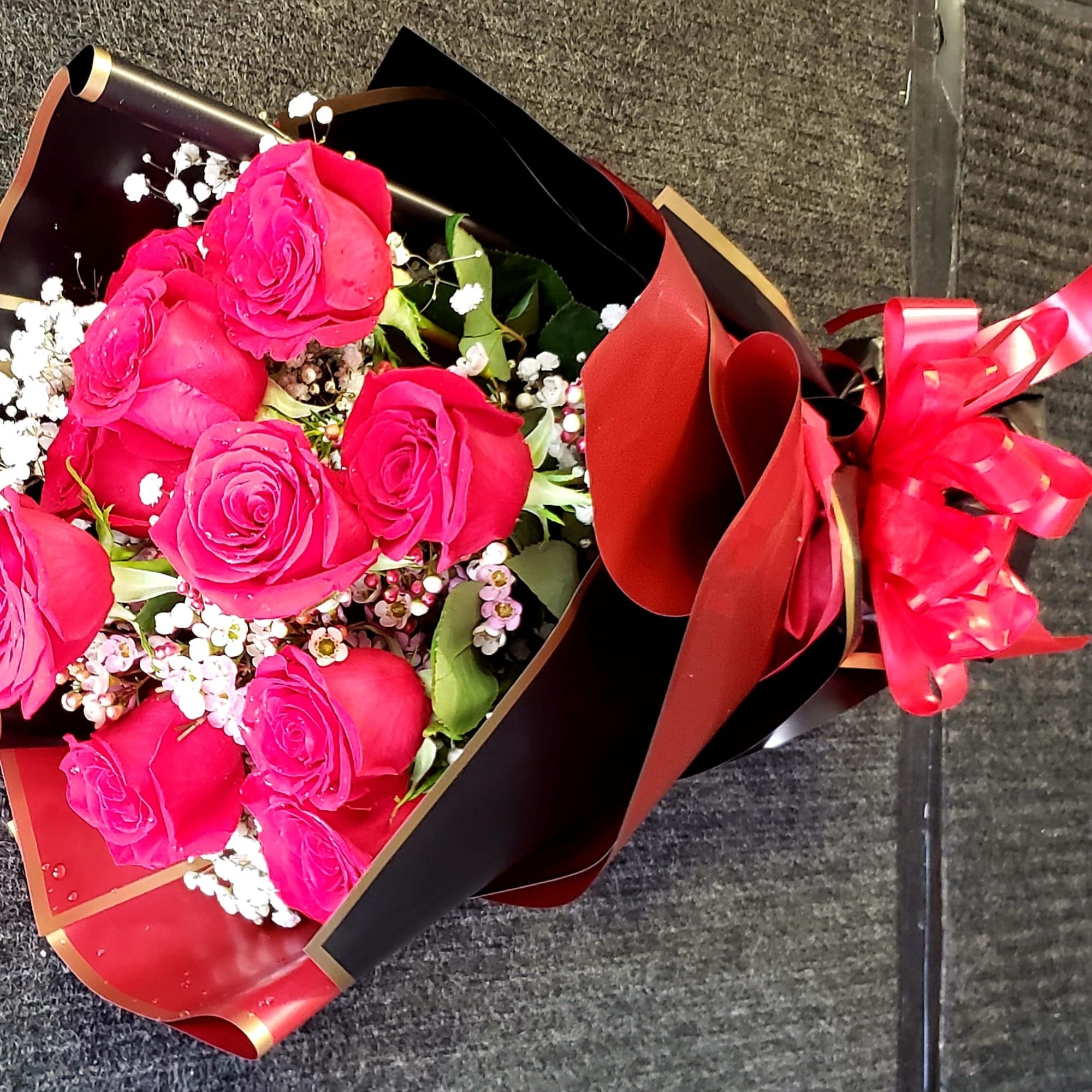 Bouquet of hot pink roses wrapped in black and red paper with a ribbon