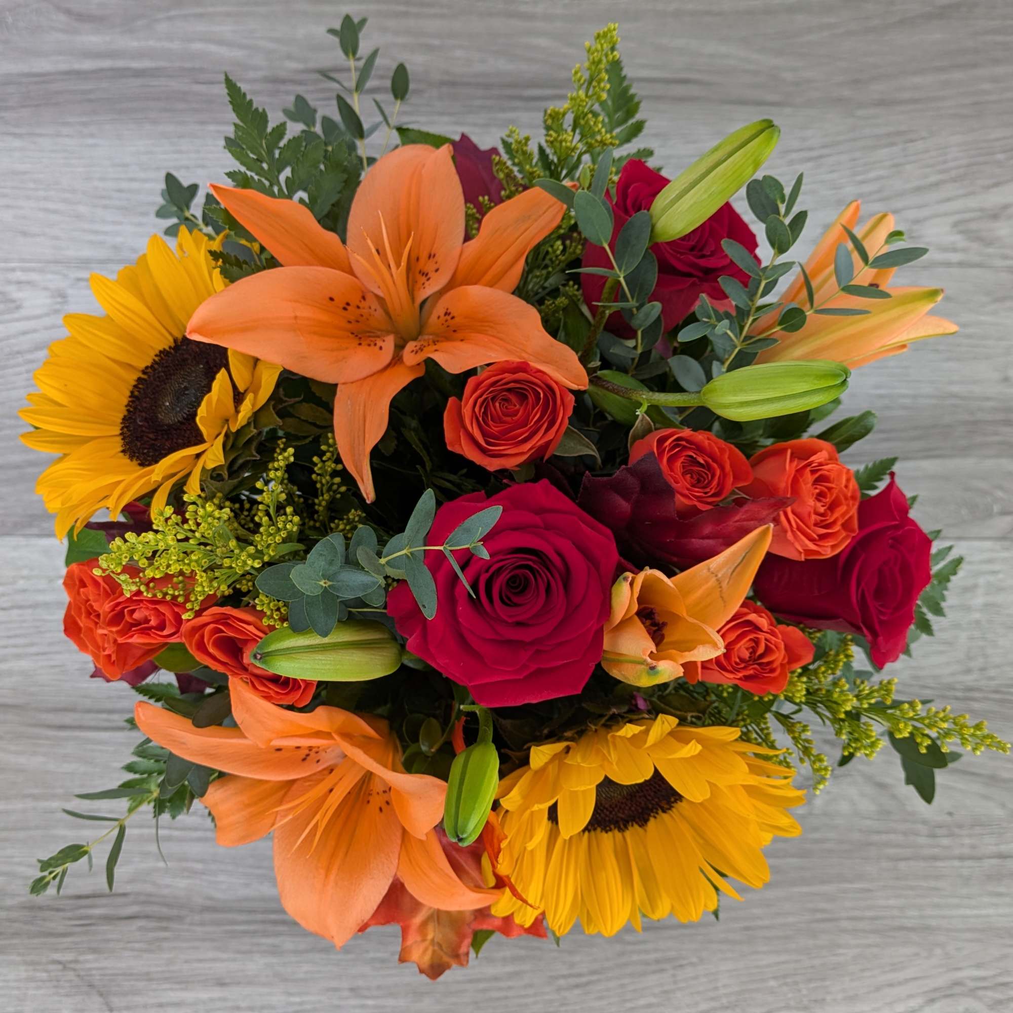 Bouquet of orange lilies, red roses, and yellow sunflowers