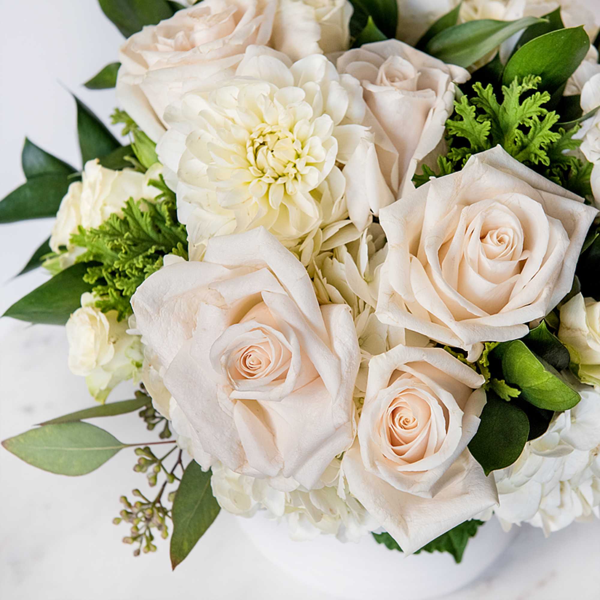 Cream roses and white blooms in a bouquet with green foliage