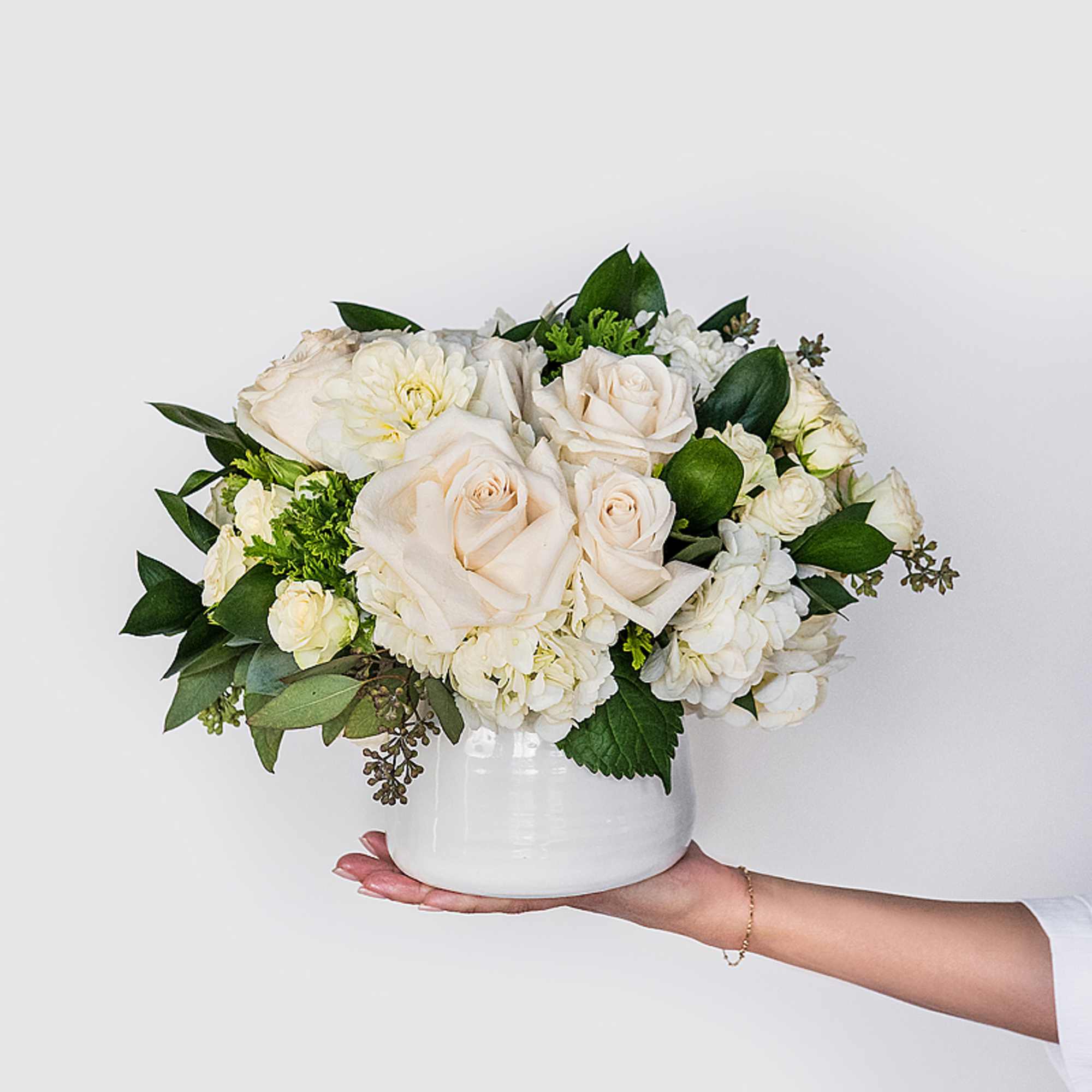 White rose and hydrangea arrangement in a white vase