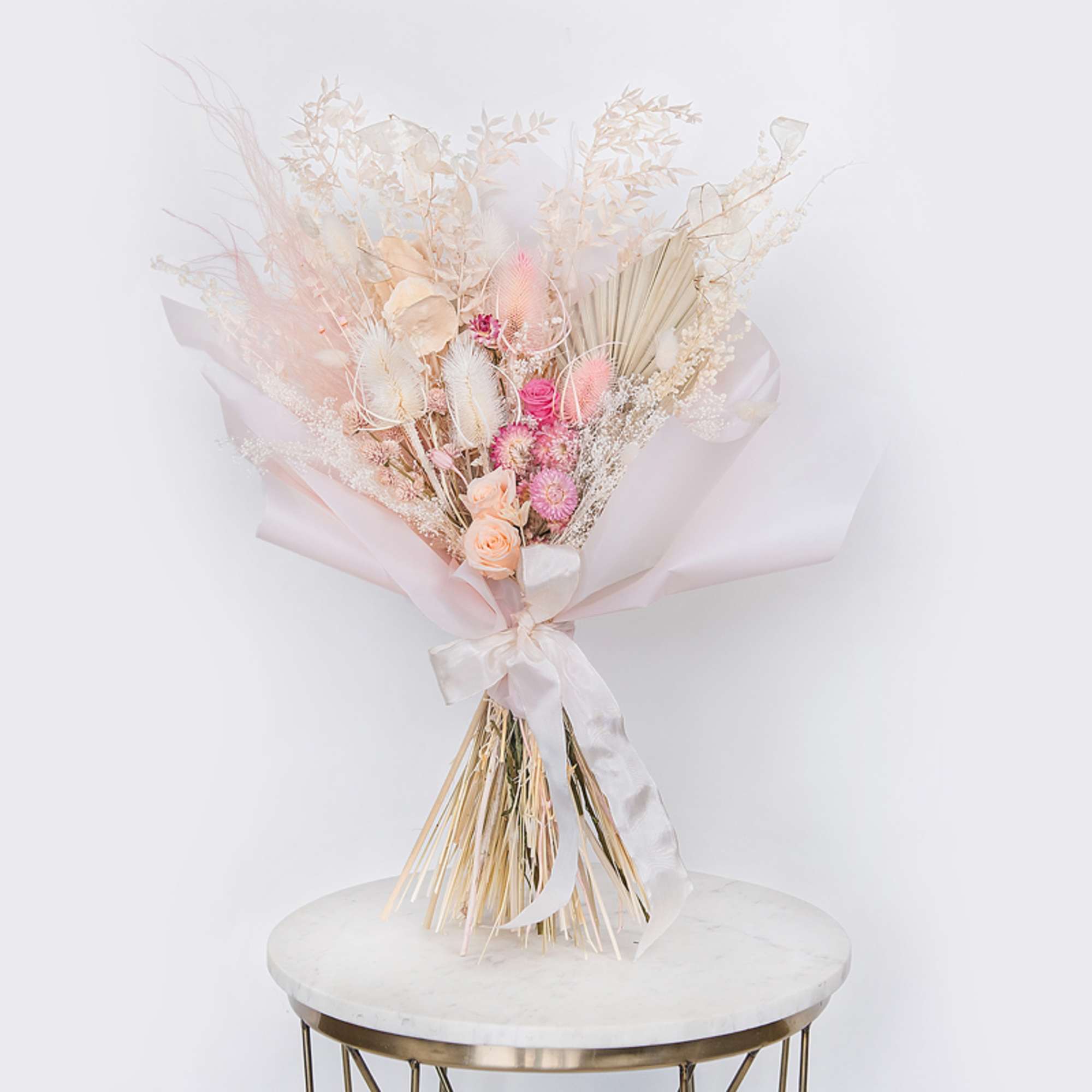 Pastel dried bouquet with pink and cream flowers wrapped in white paper