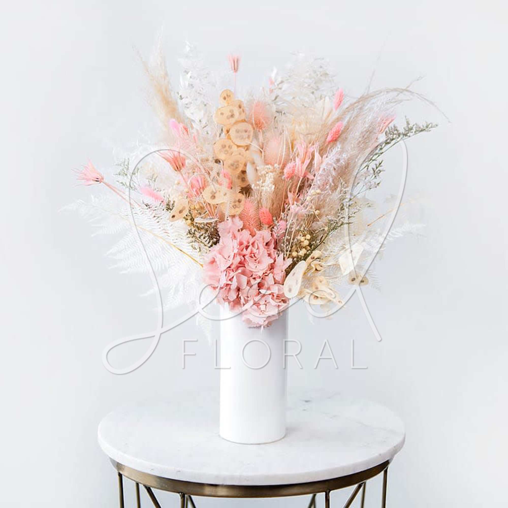 Pink dried floral arrangement in a white vase