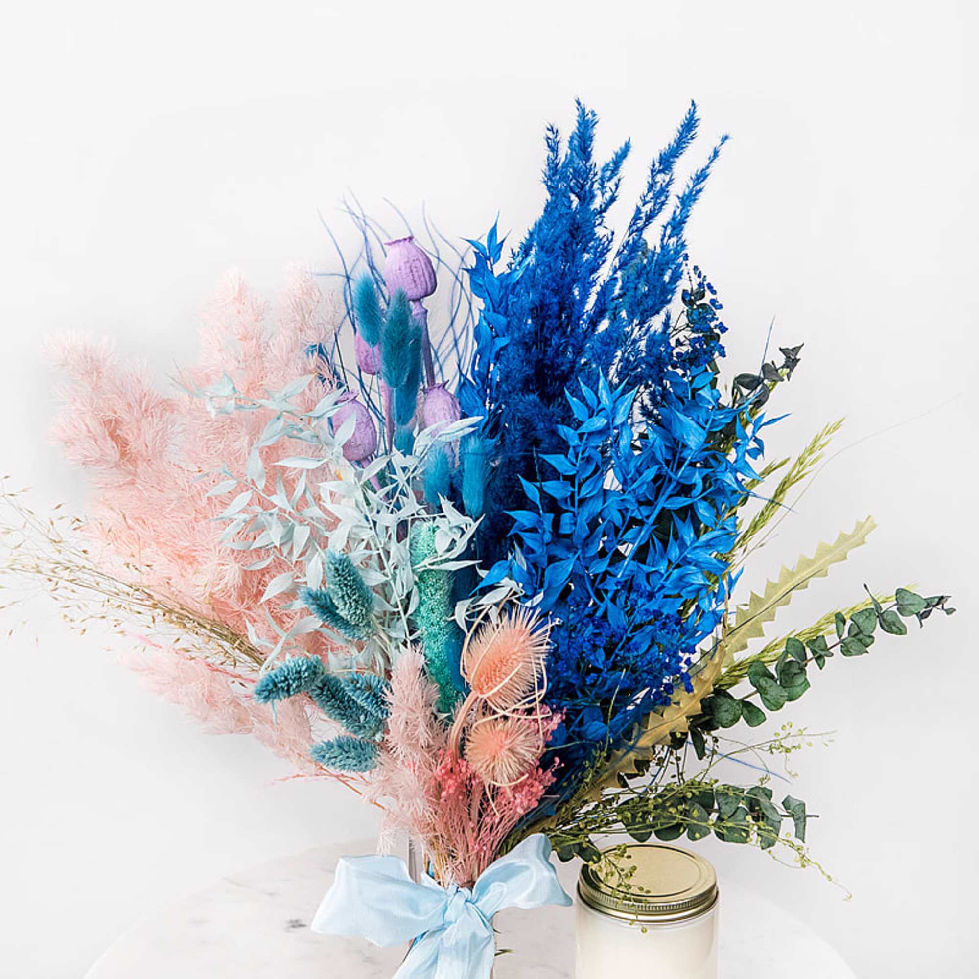 Colorful dried bouquet in a glass jar with a blue ribbon
