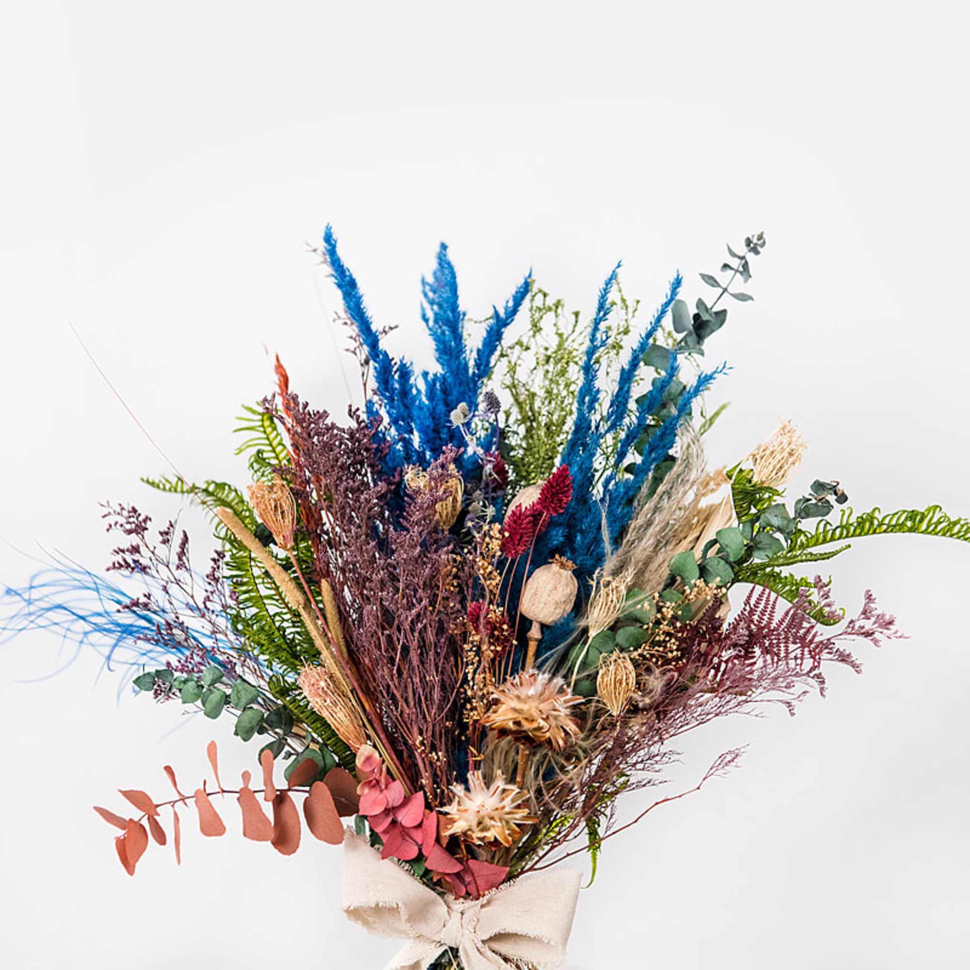 Dried floral bouquet with blue and burgundy accents tied with a beige ribbon