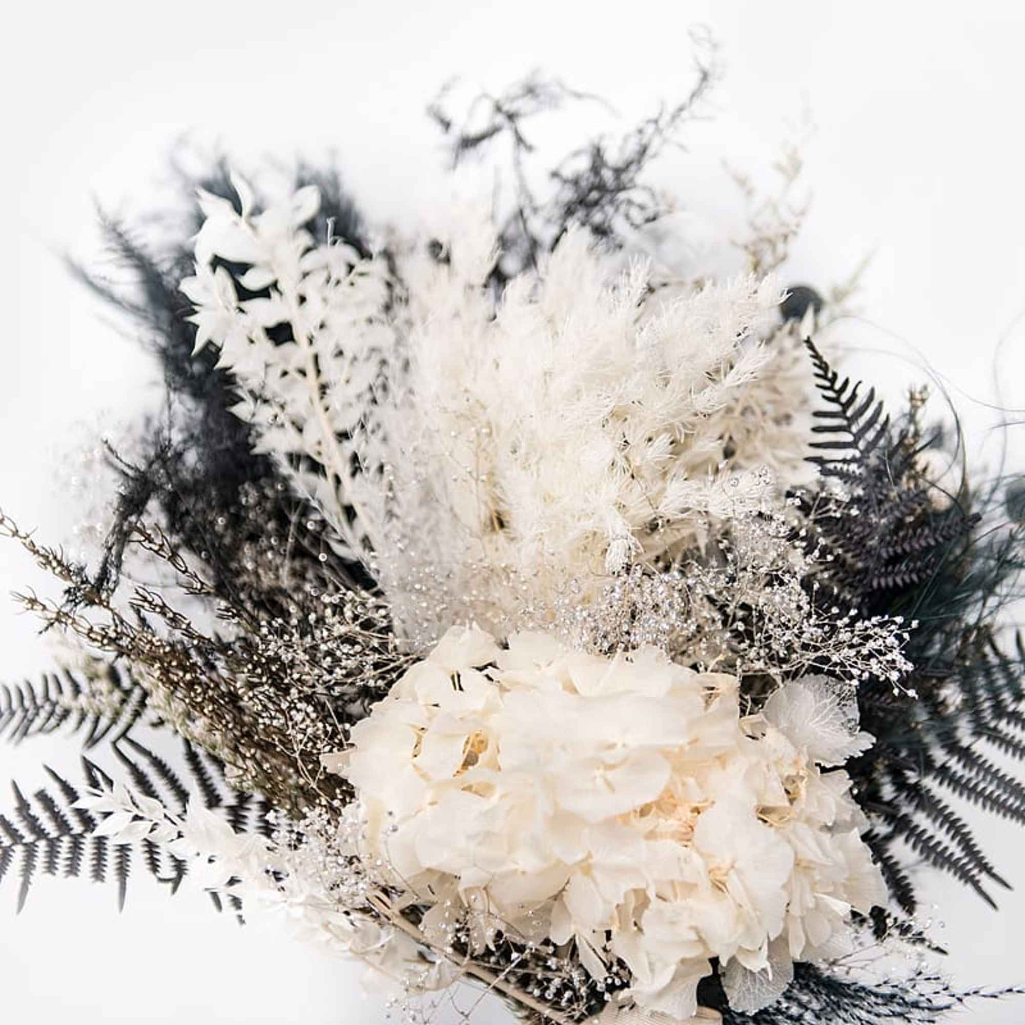 White floral bouquet with feathery accents and dark fern-like foliage
