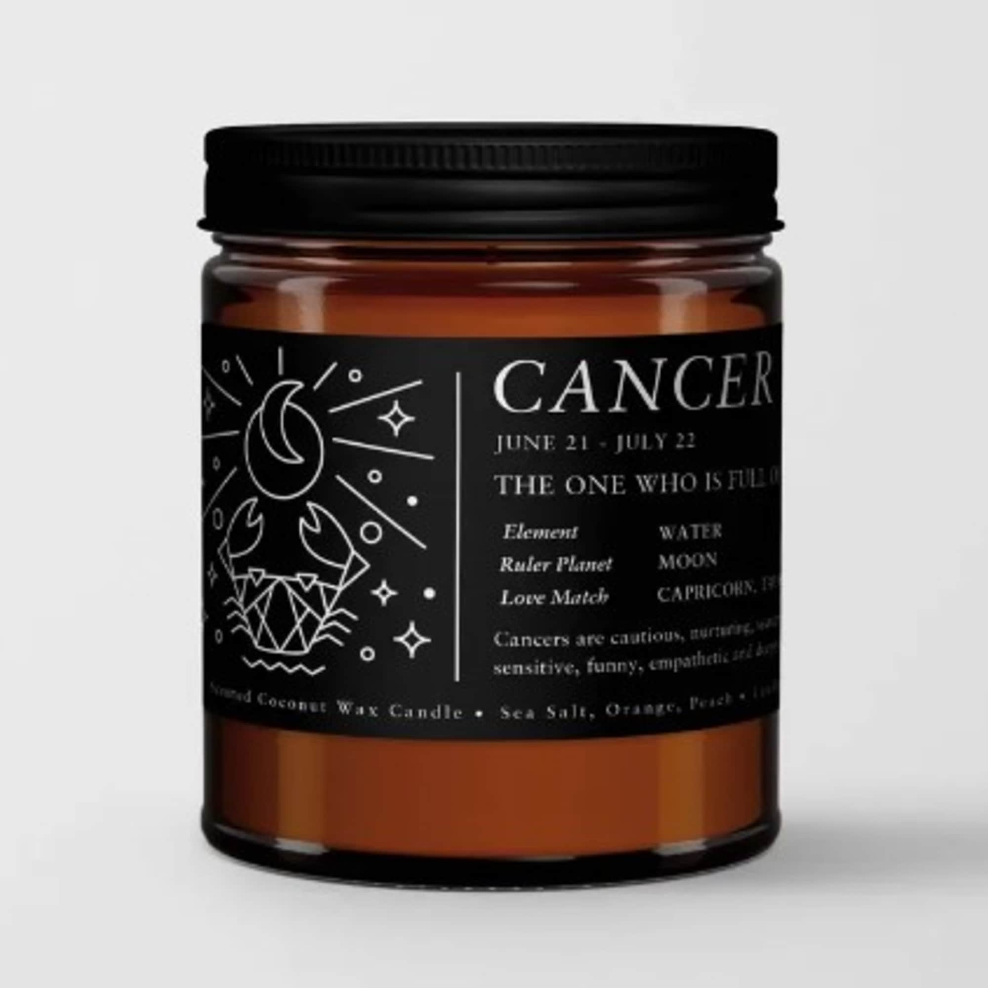 Amber jar candle with a black label and Cancer zodiac design