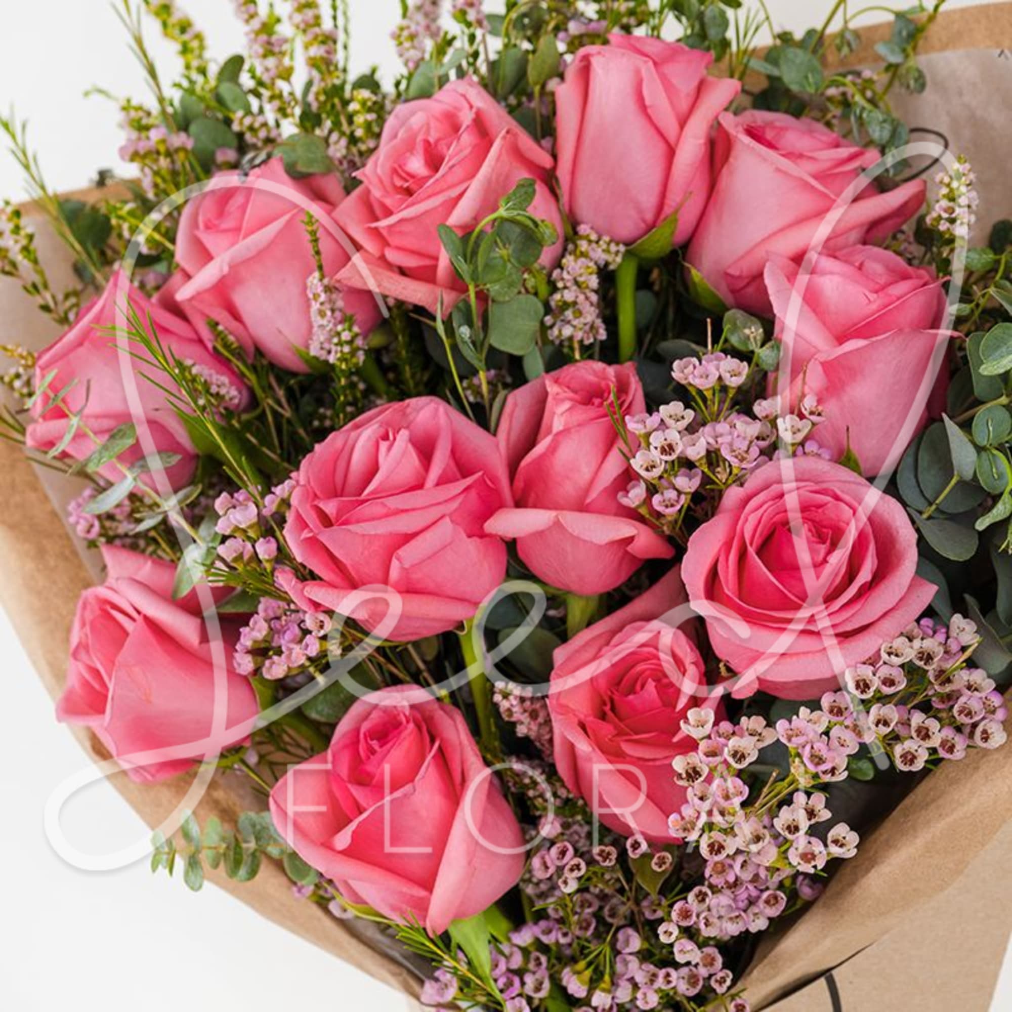 Bouquet of pink roses with small pink filler flowers wrapped in kraft paper