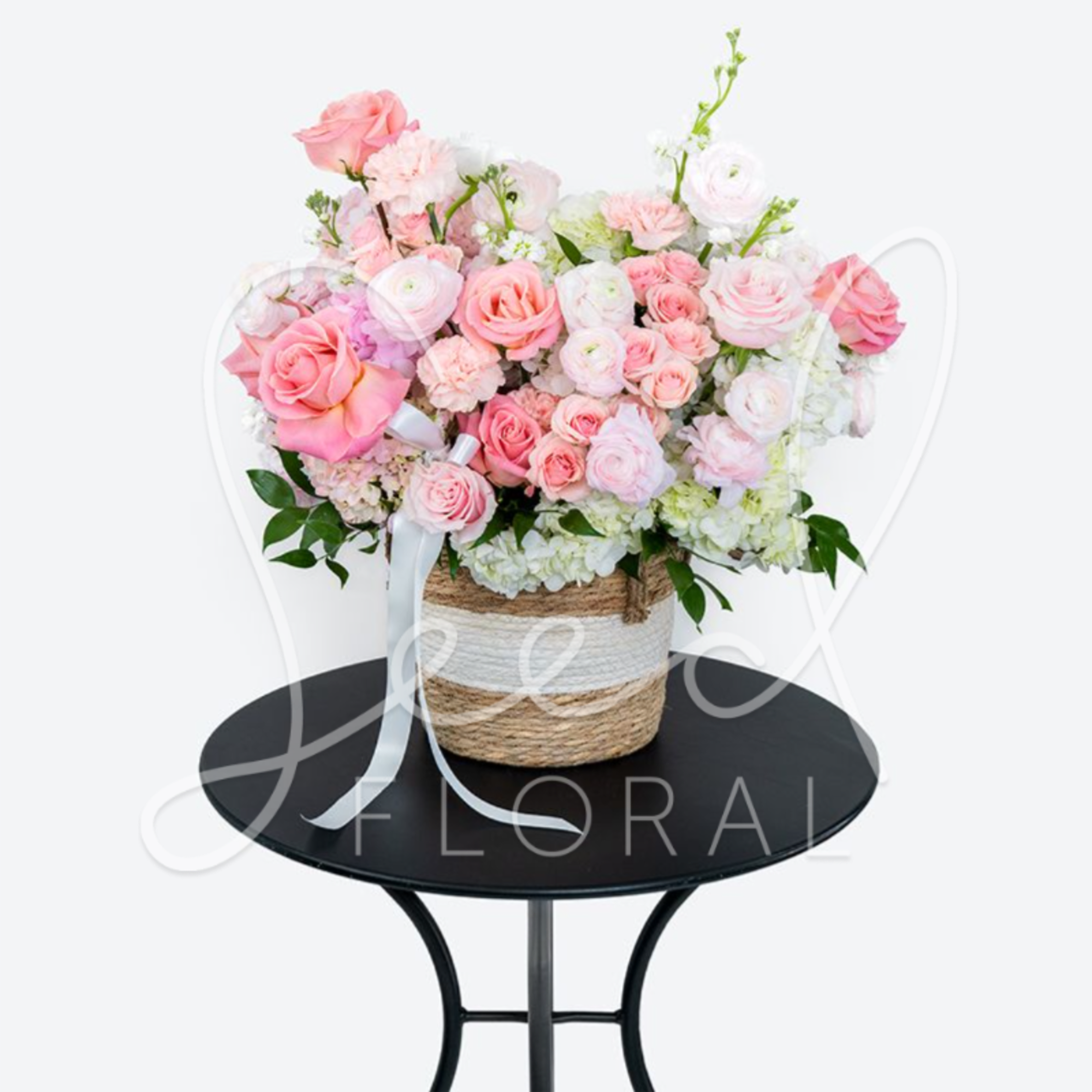 Pink and white rose arrangement in a woven basket