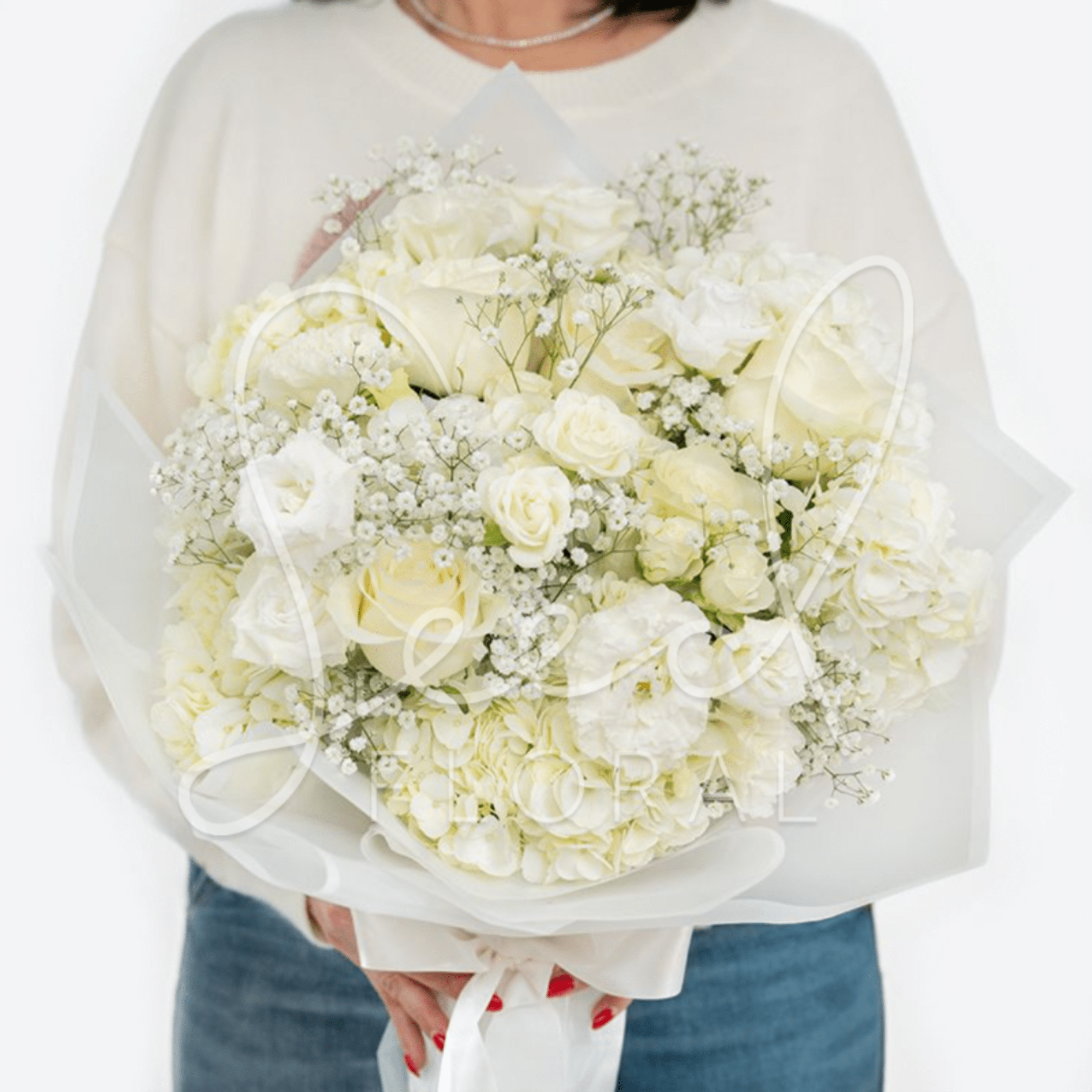 Large hand-tied bouquet of white roses, hydrangeas, and filler flowers wrapped in translucent white paper