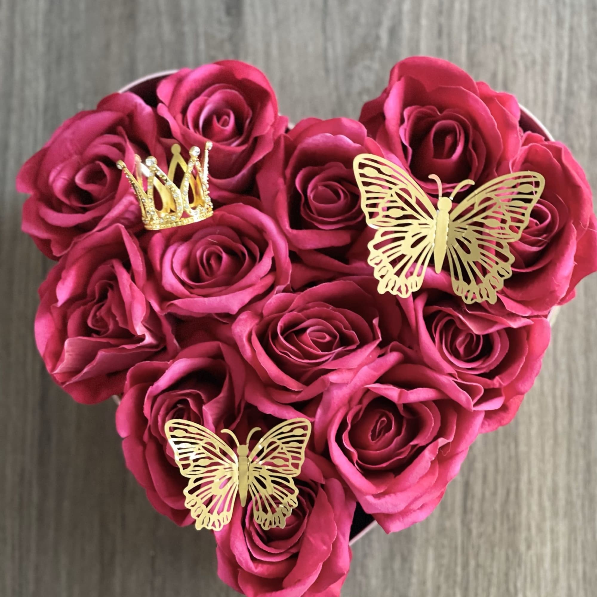 Heart-shaped bouquet of pink roses with gold butterfly and crown picks