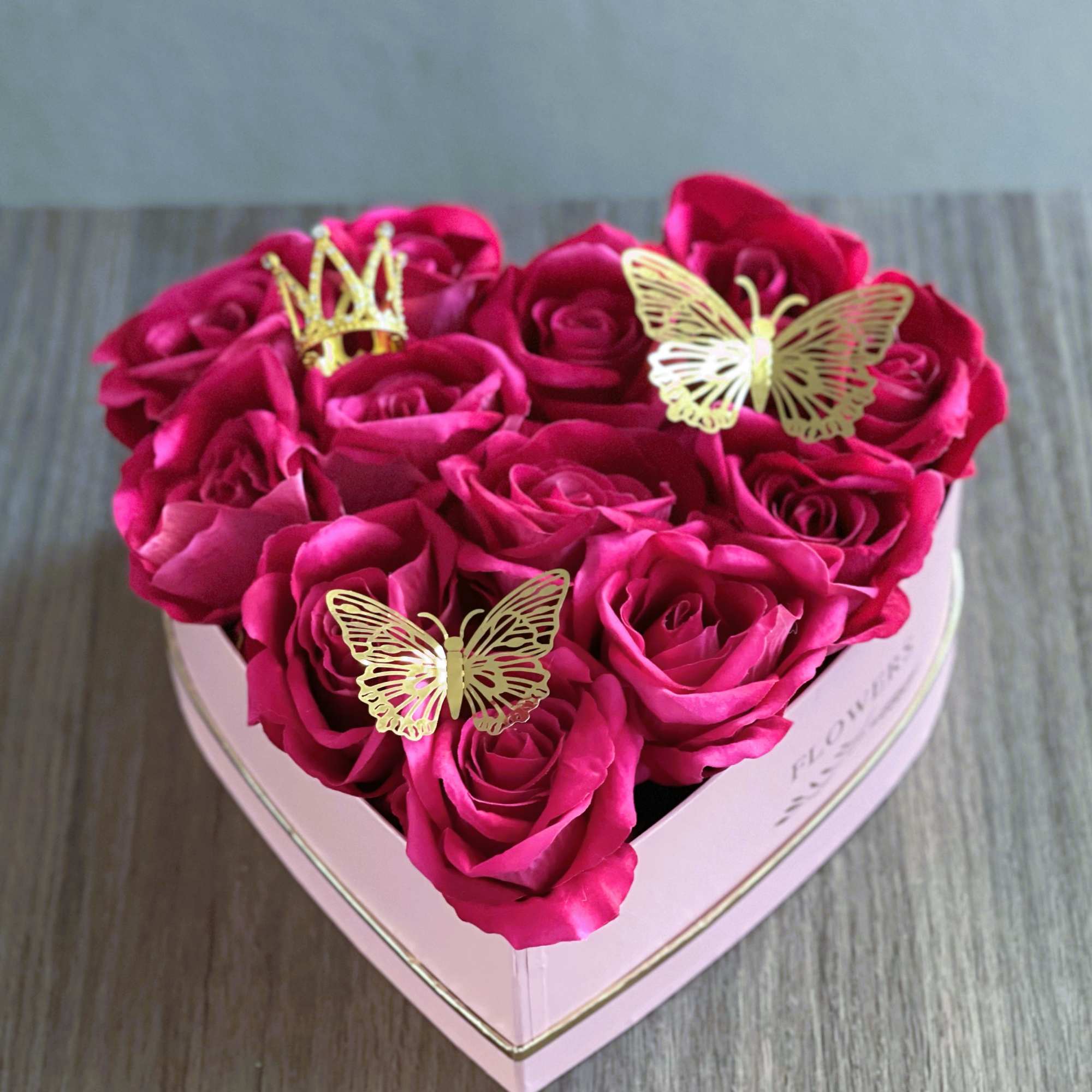 Heart-shaped box of hot pink roses with gold butterfly decorations