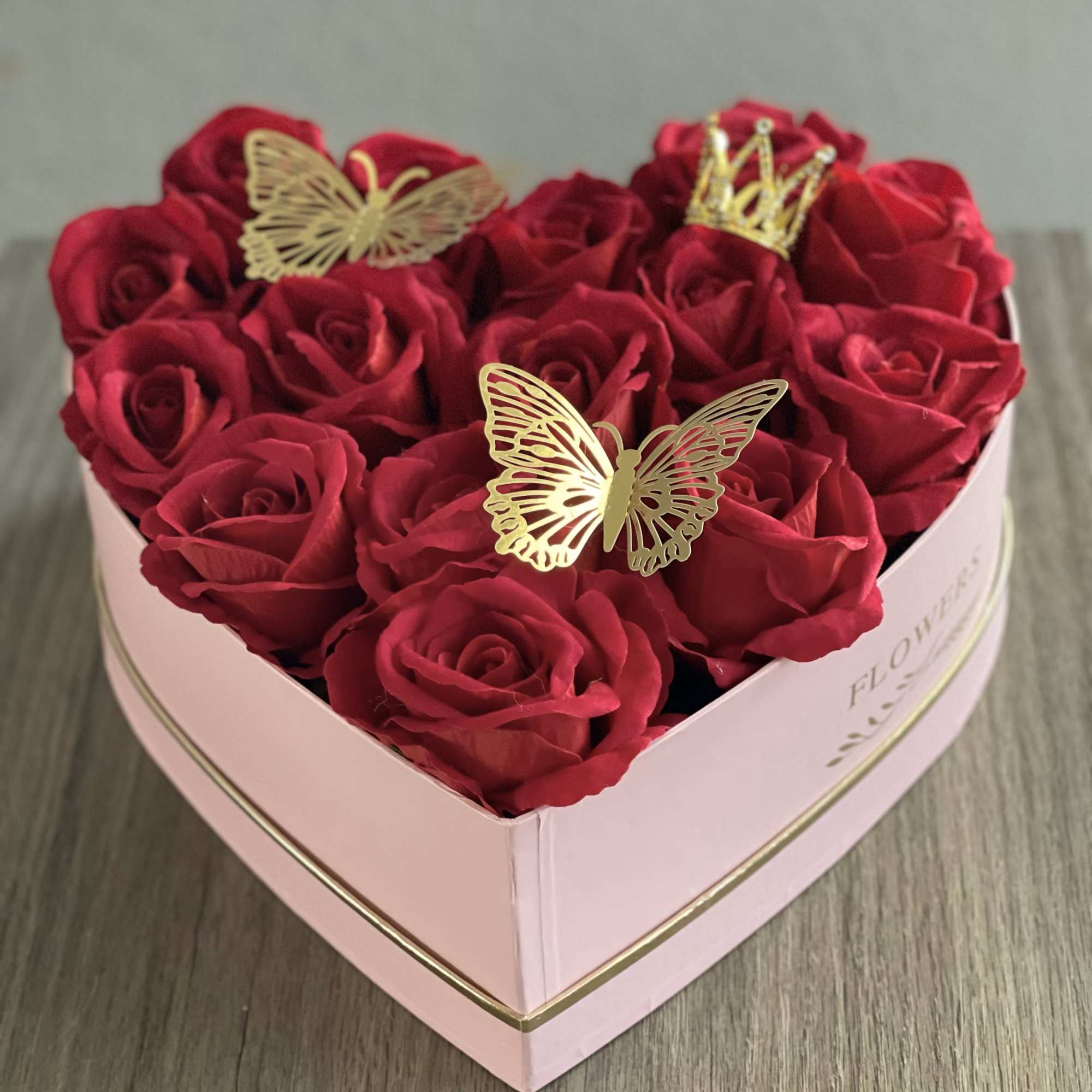 Heart-shaped box of red roses with gold butterfly and crown decorations