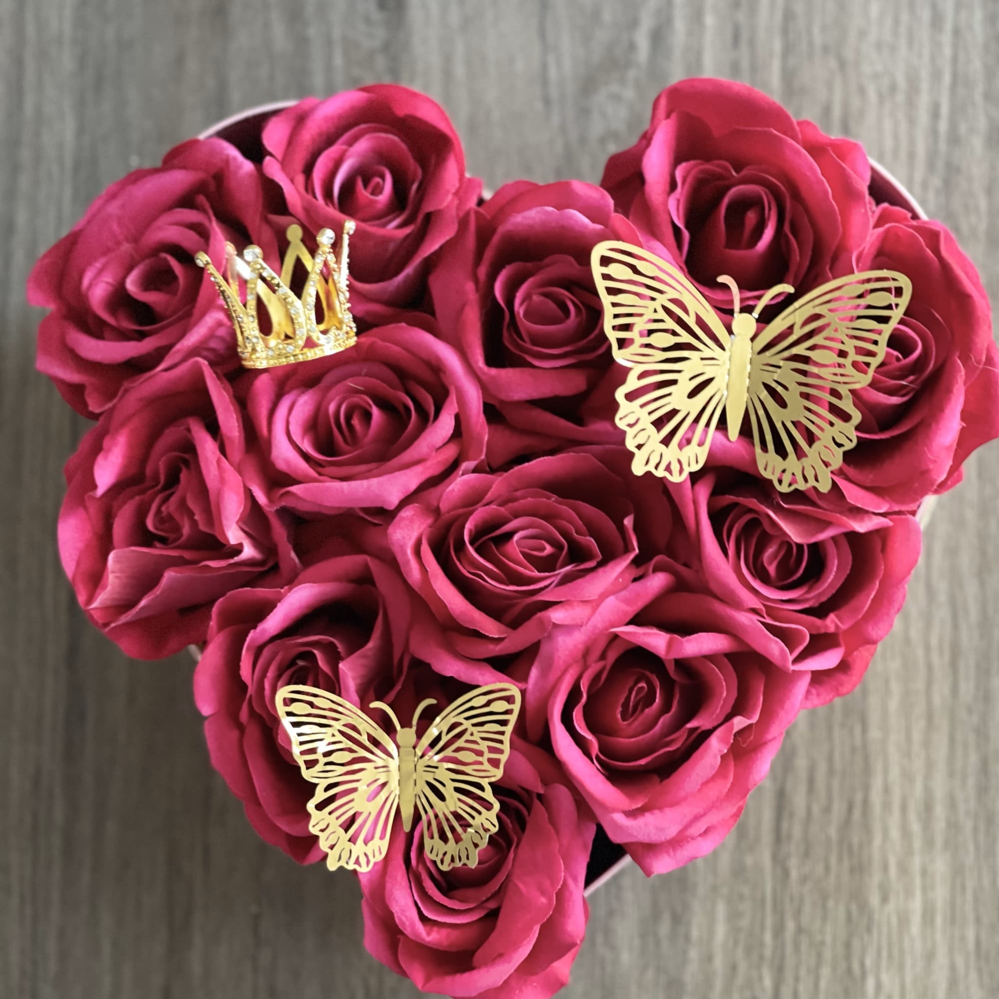 Heart-shaped bouquet of pink roses with gold butterfly and crown decorations