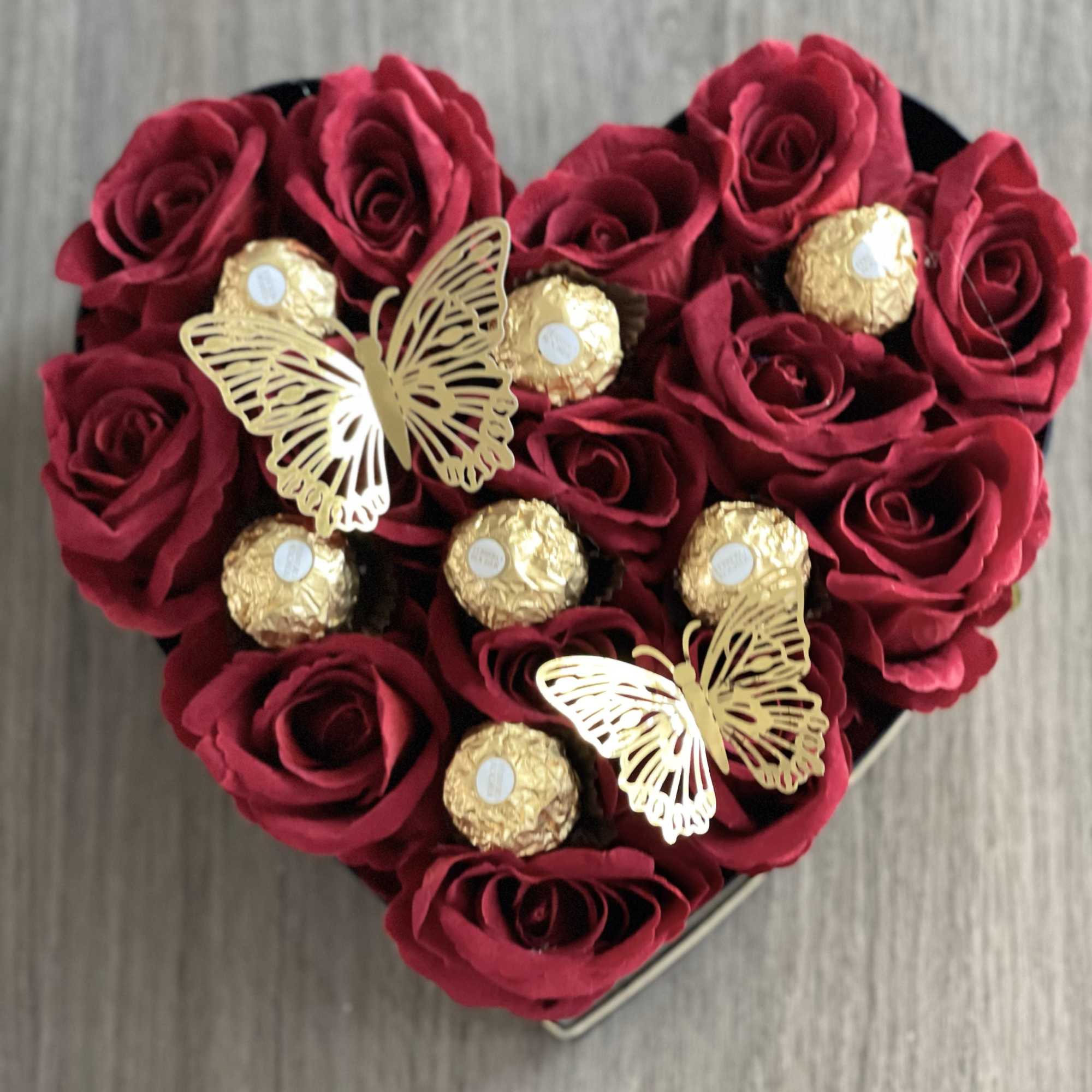 Heart-shaped box of red roses with gold-wrapped chocolates and butterfly decorations