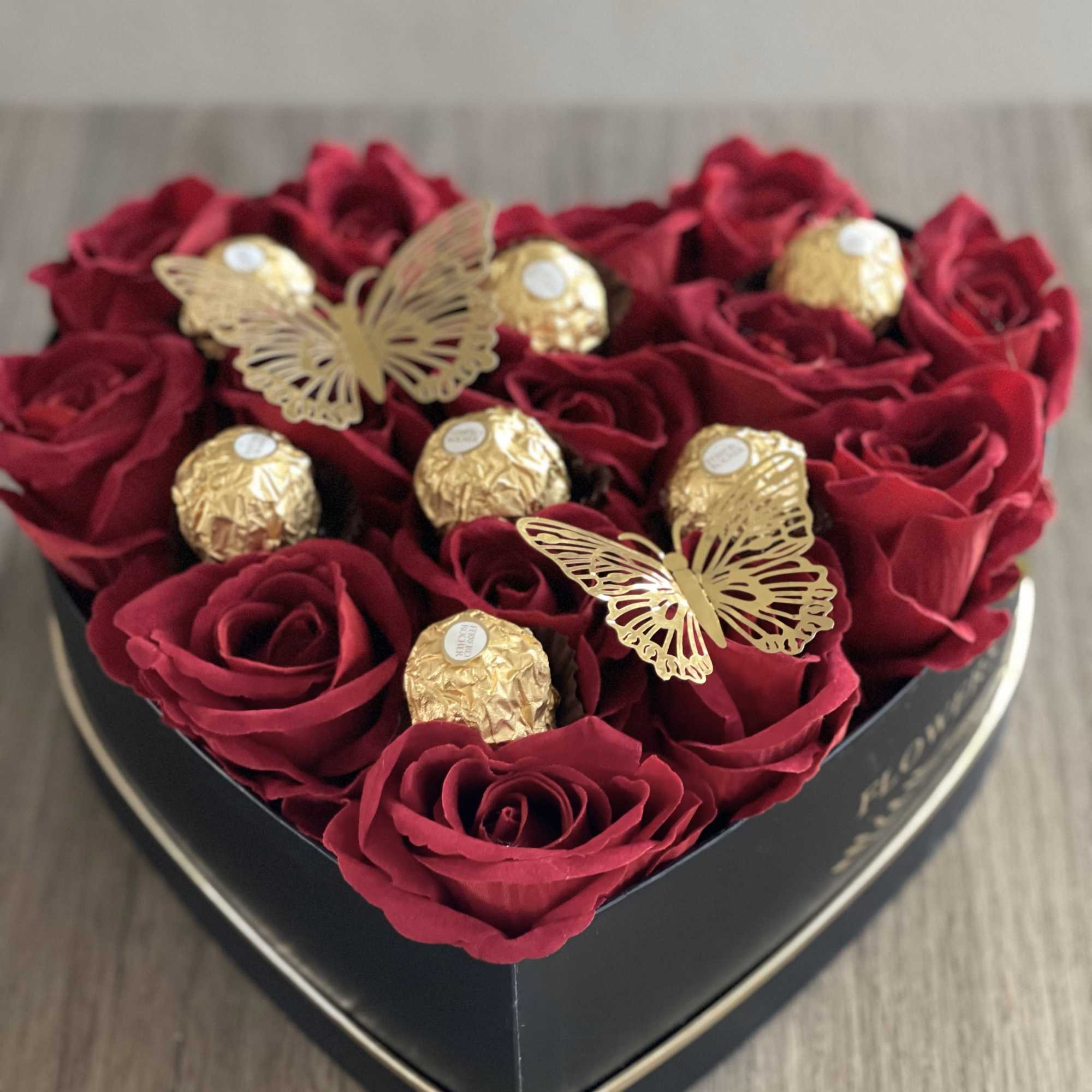 Heart-shaped box of red roses with gold chocolates and butterfly decorations