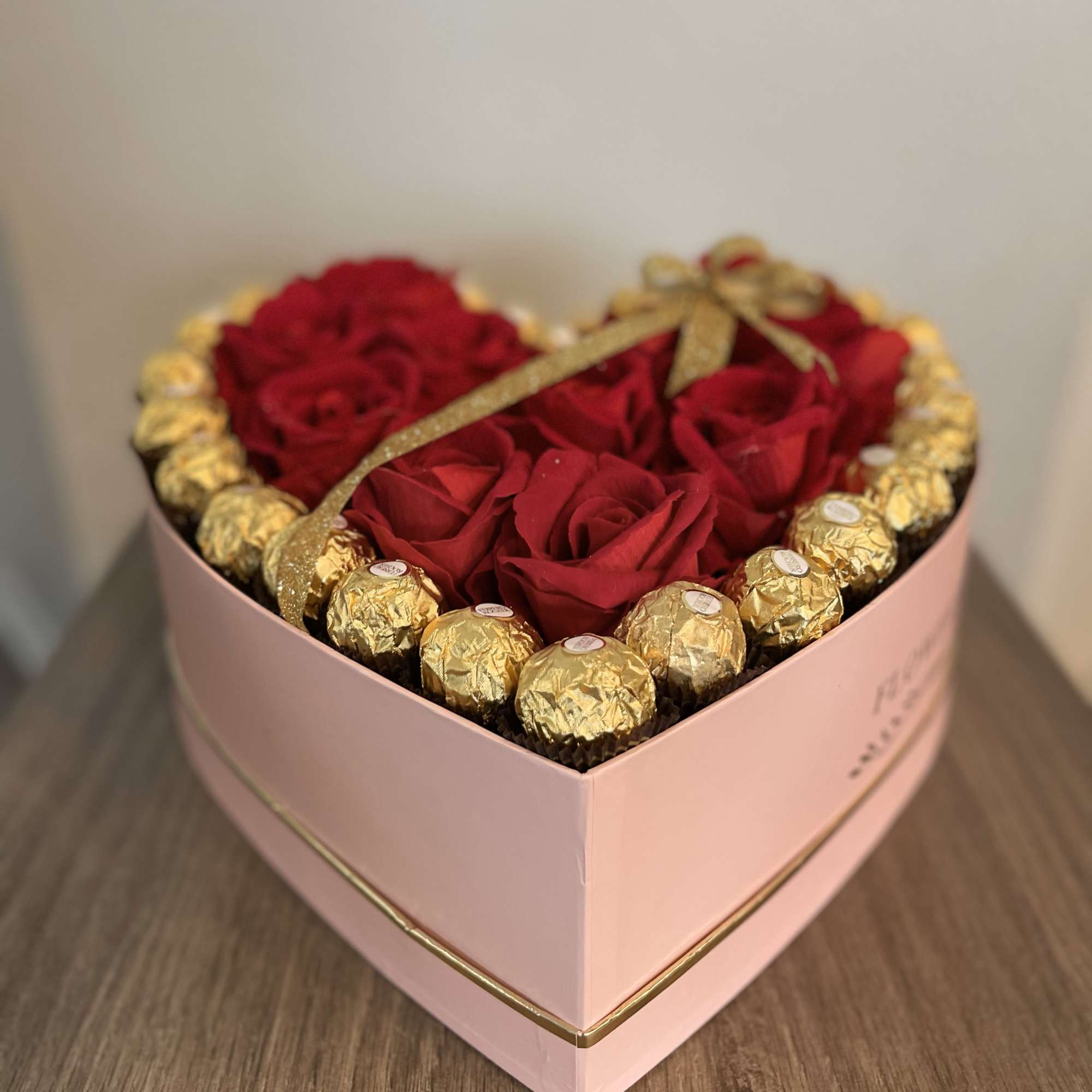 Heart-shaped box of red roses with gold-wrapped chocolates