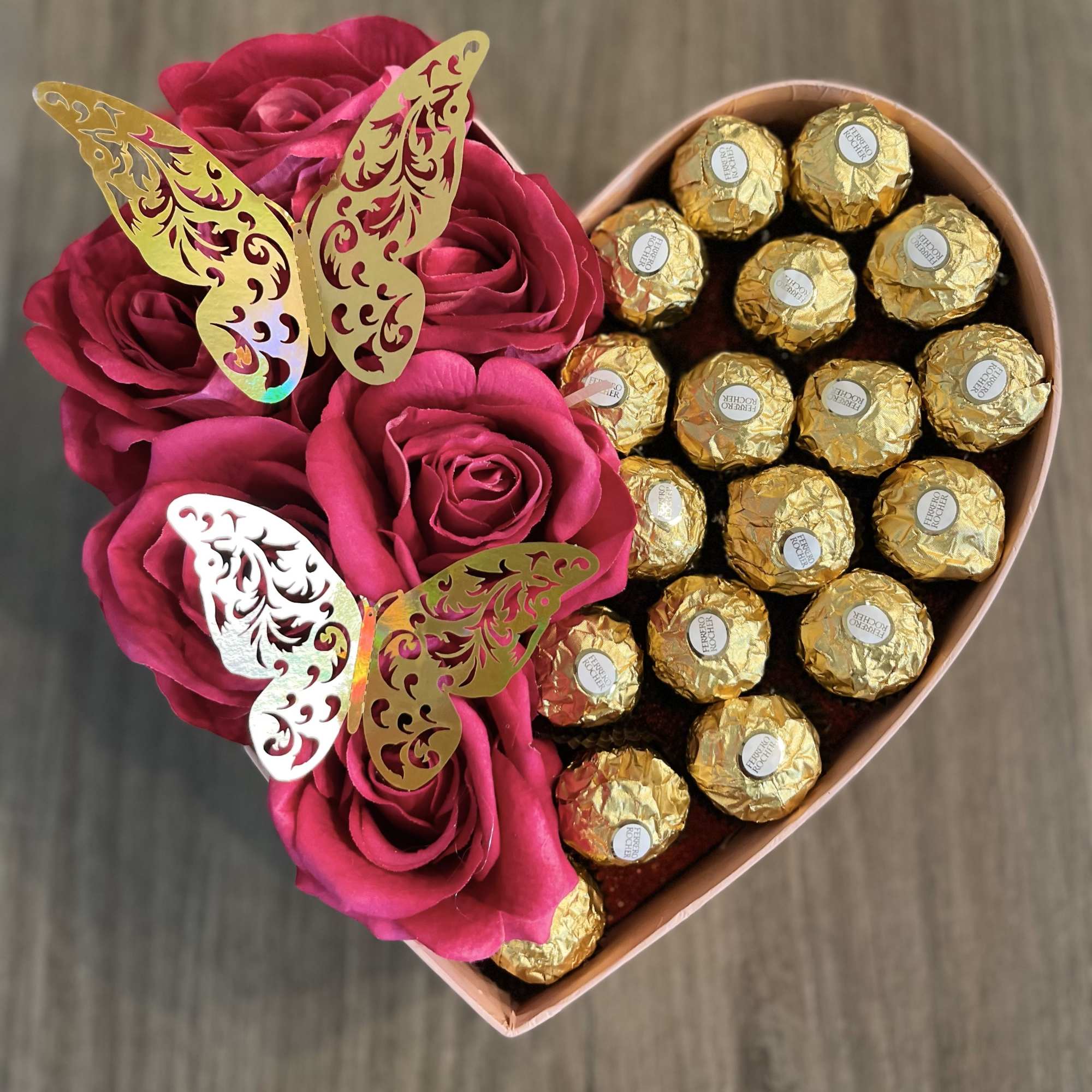 Heart-shaped box with pink roses and gold-wrapped chocolates