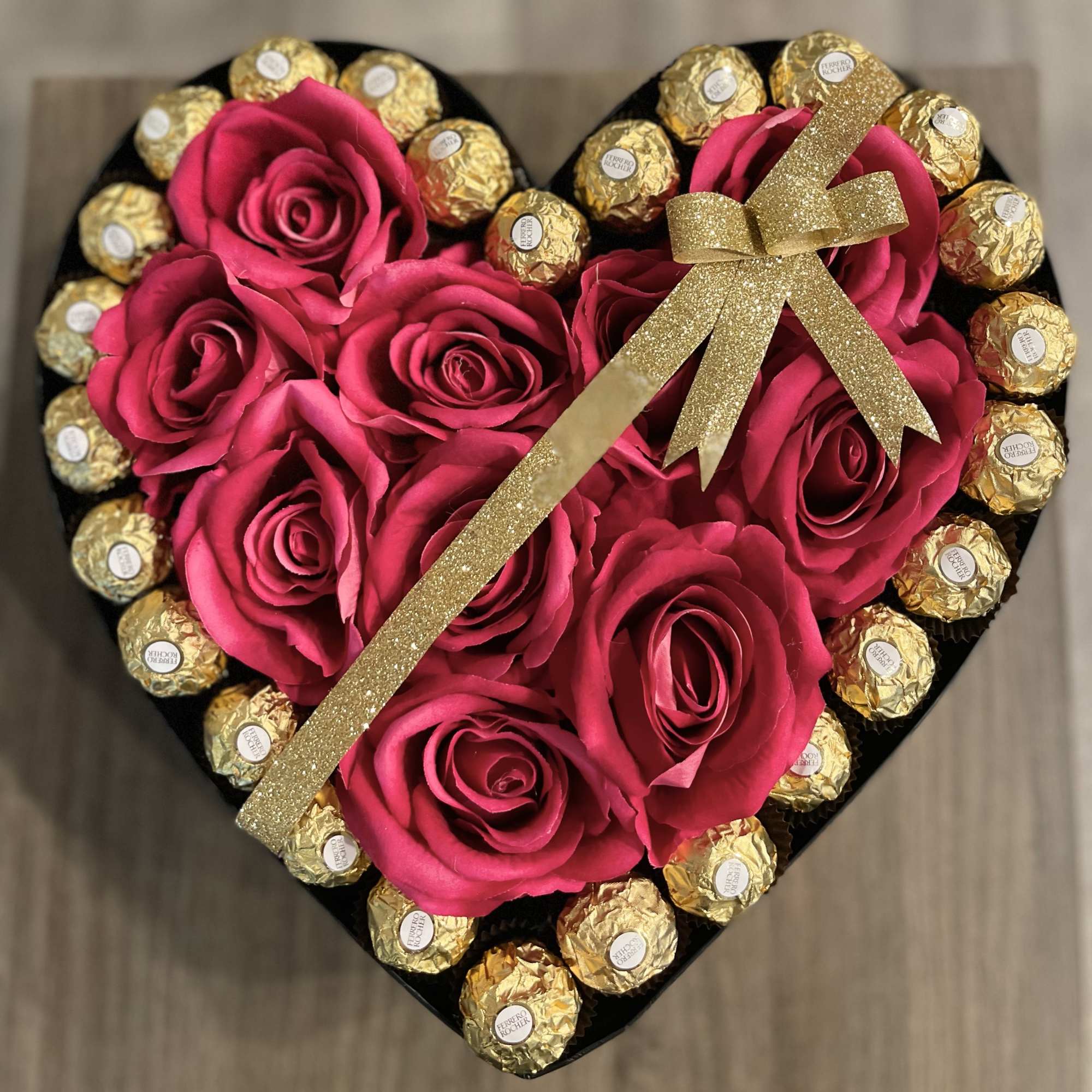Heart-shaped box with pink roses and gold-wrapped chocolates