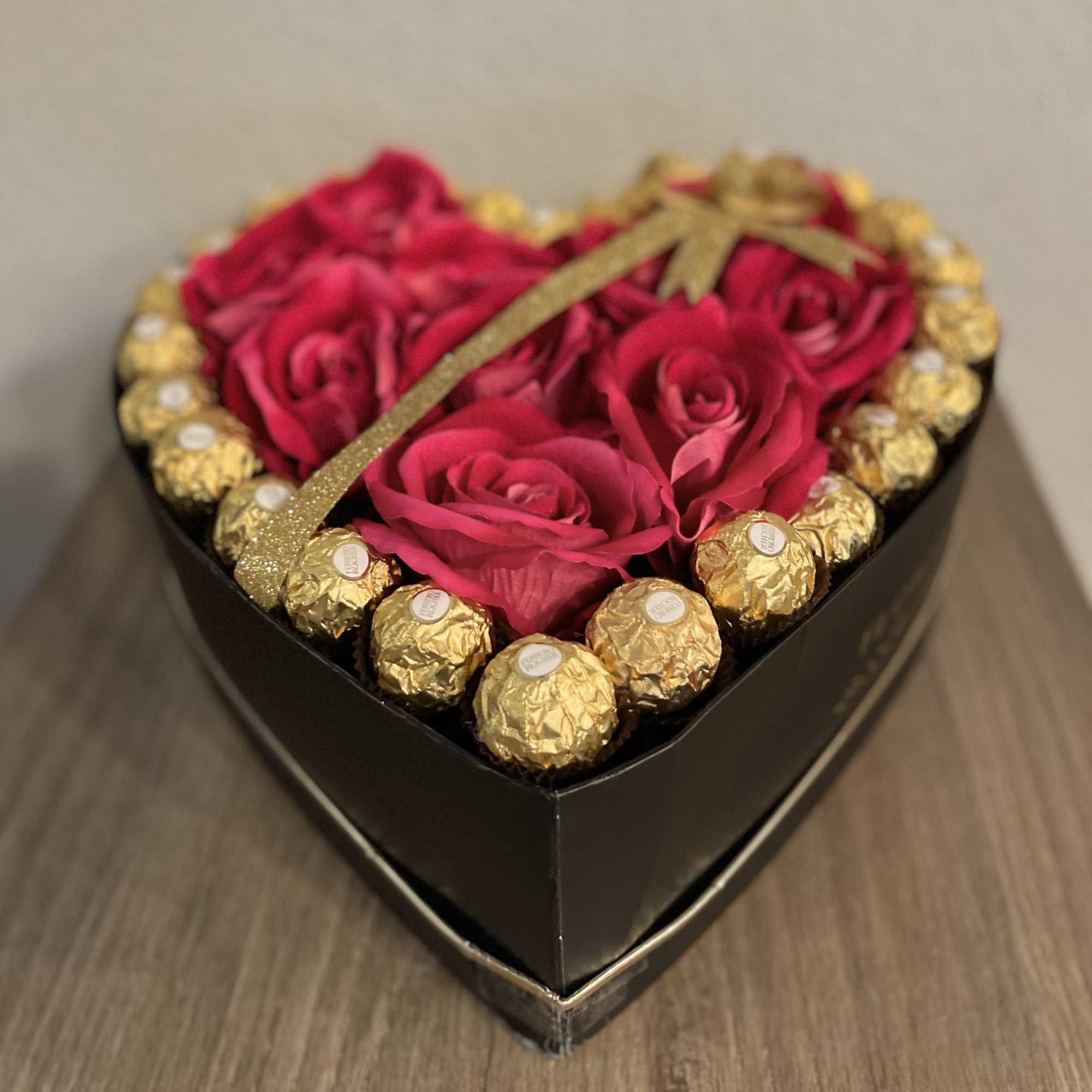 Heart-shaped box of pink roses with gold-wrapped chocolates