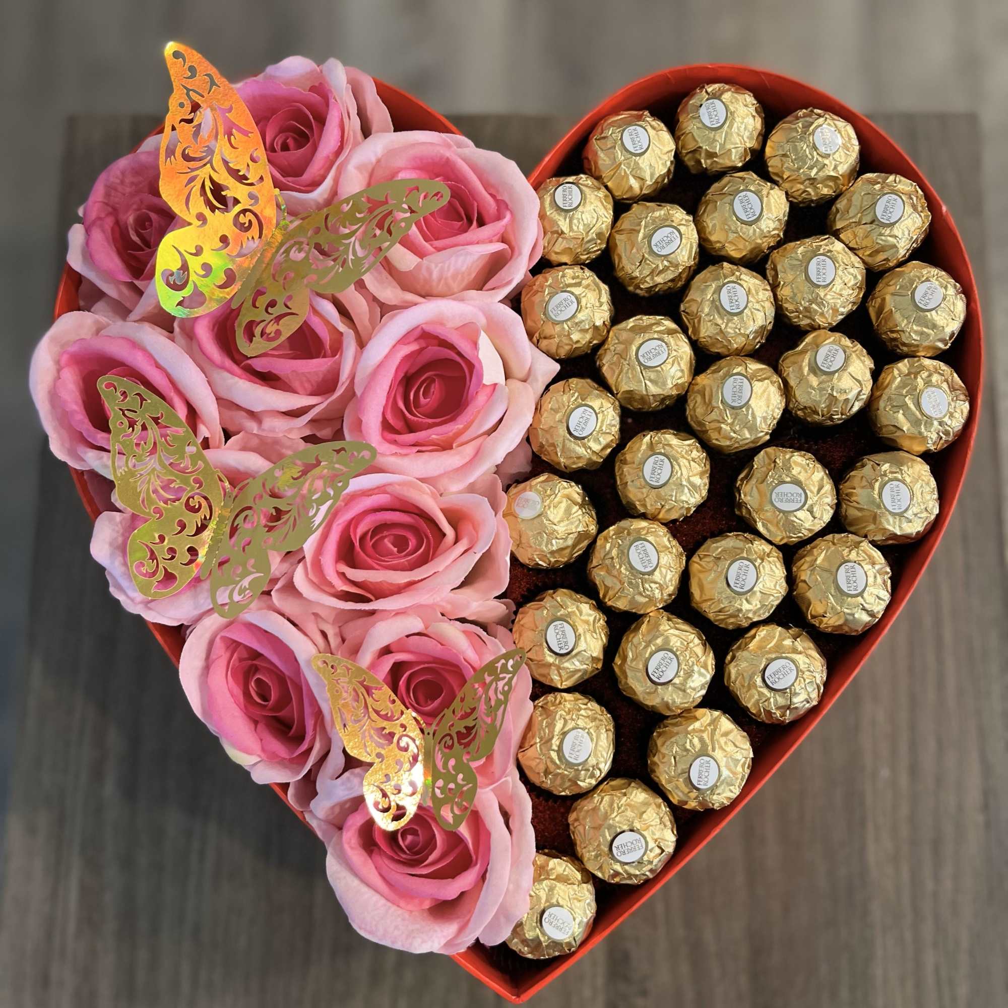 Heart-shaped box with pink roses and gold-wrapped chocolates