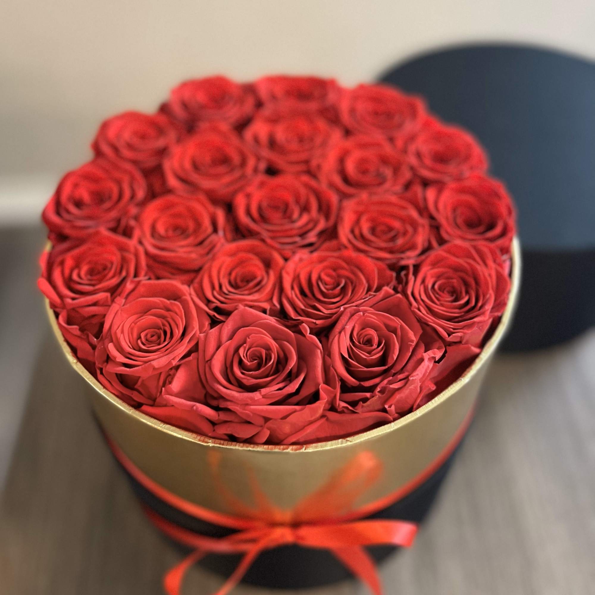 Round box of red roses tied with a red ribbon
