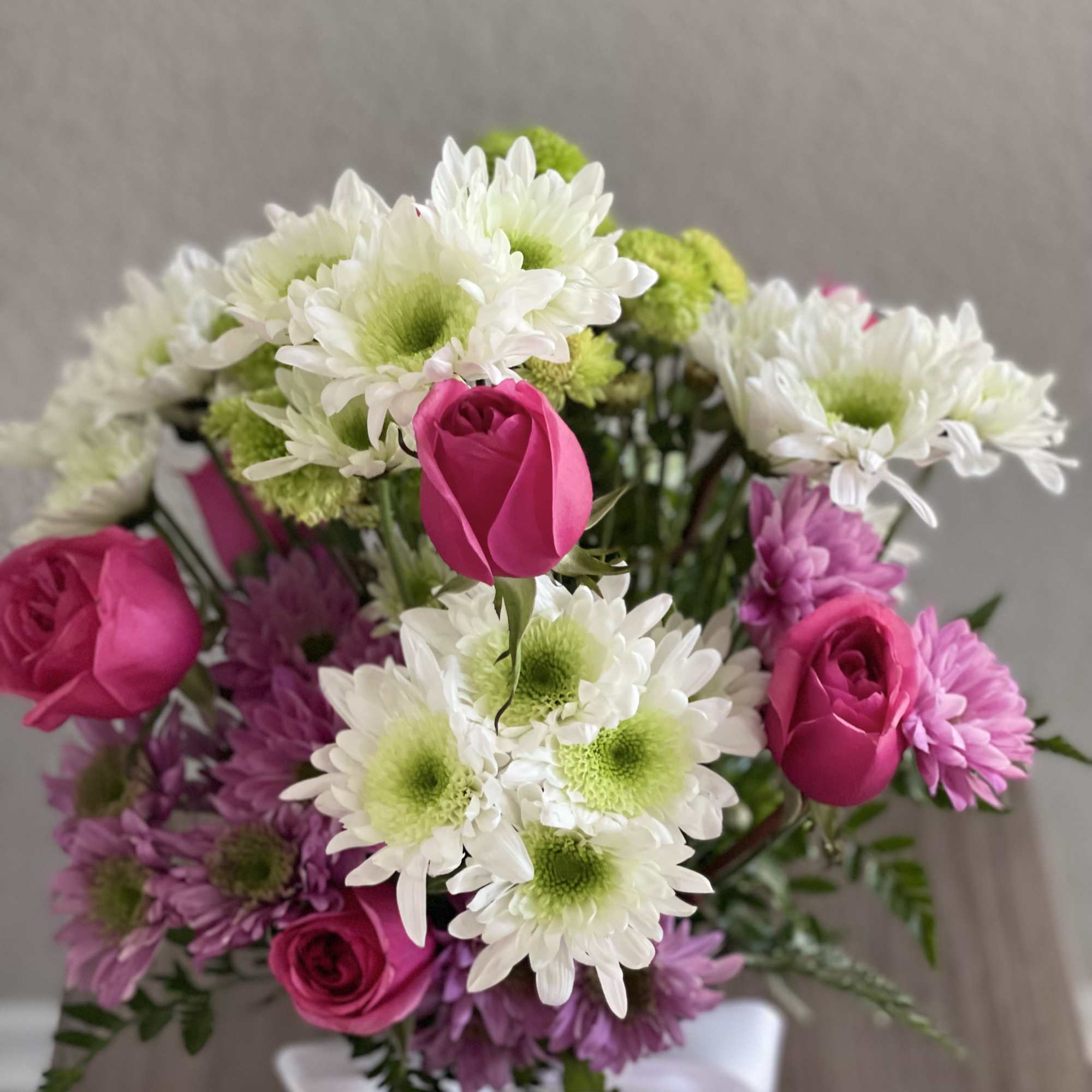 Bouquet of pink roses and white daisies with a white ribbon