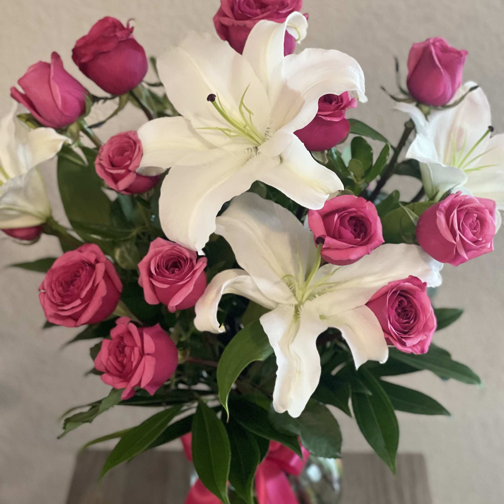 Pink roses and white lilies in a glass vase with a pink ribbon, photo 2 of 2