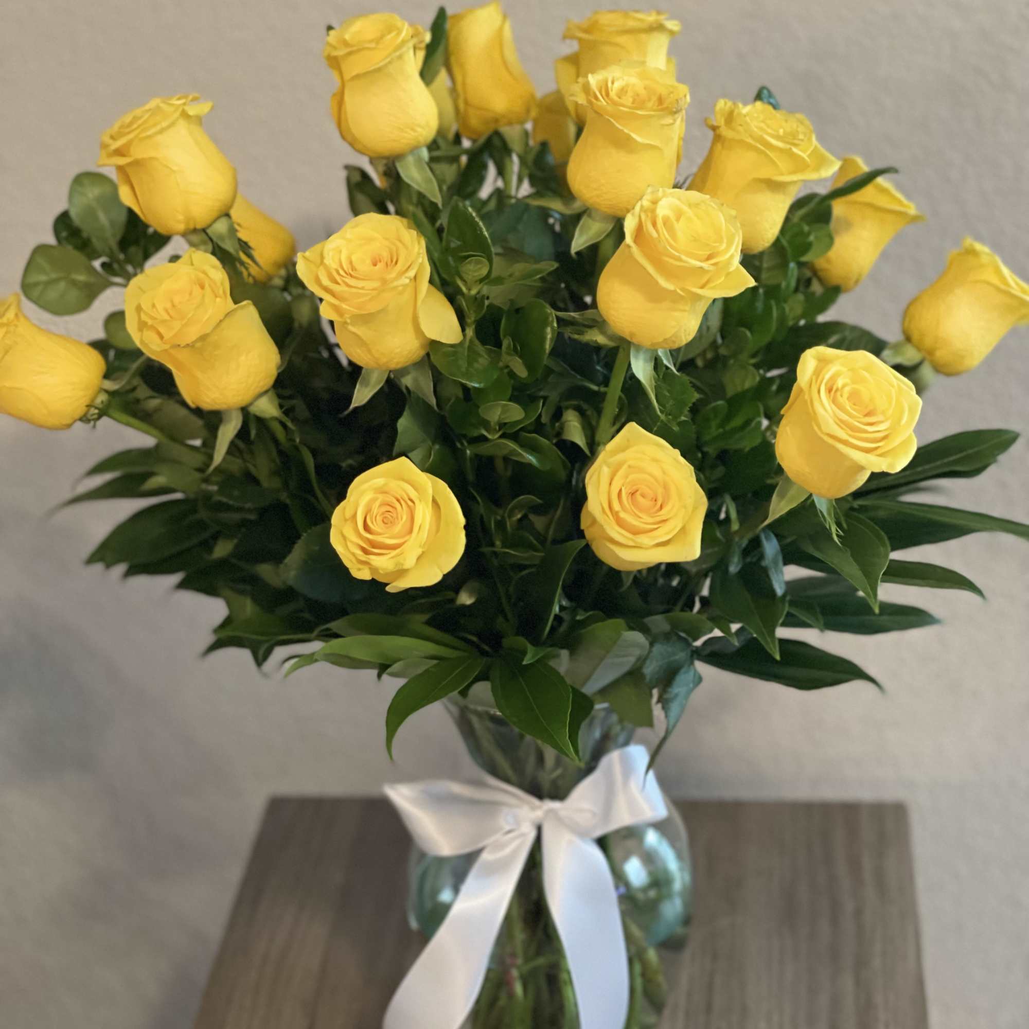 Yellow roses in a glass vase tied with a white ribbon