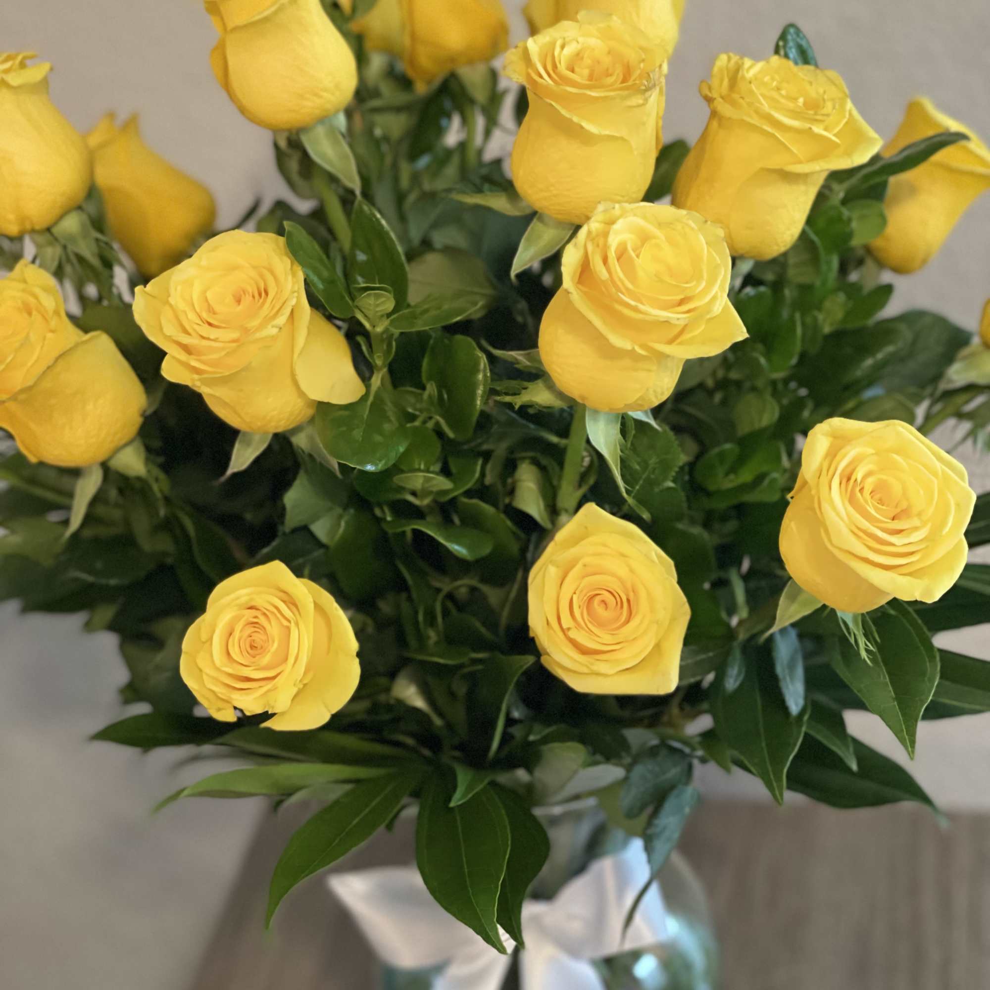 Bouquet of yellow roses in a glass vase with a white ribbon