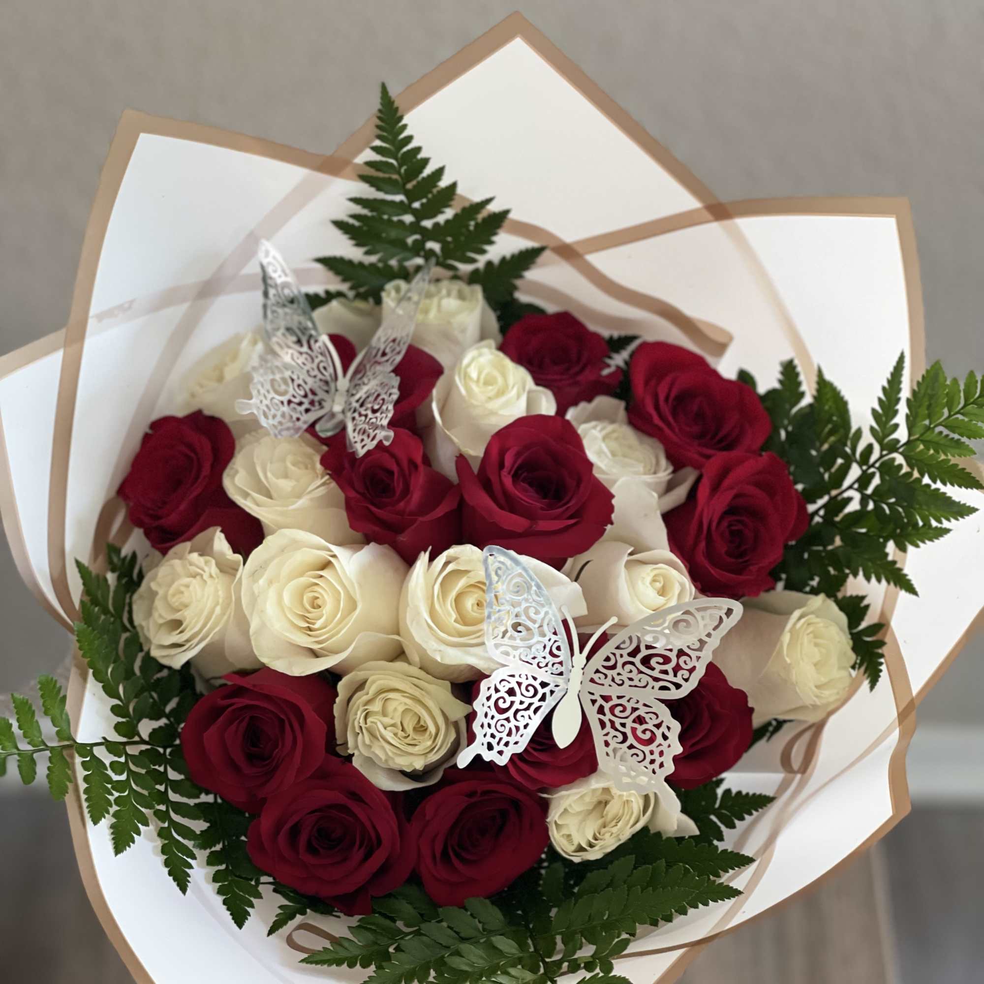 Bouquet of red and white roses with fern accents and butterfly decorations